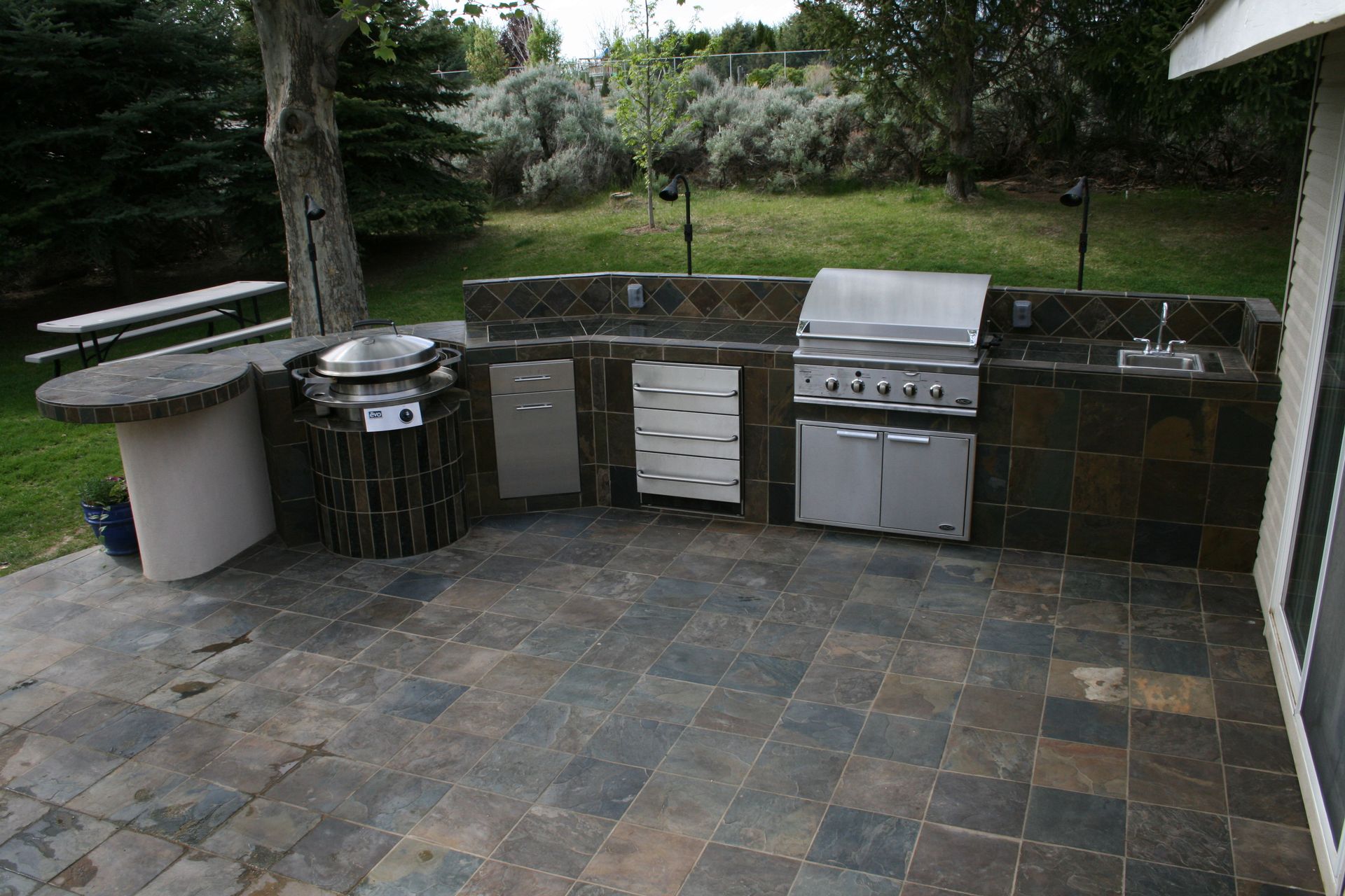 A large outdoor kitchen with a grill and sink