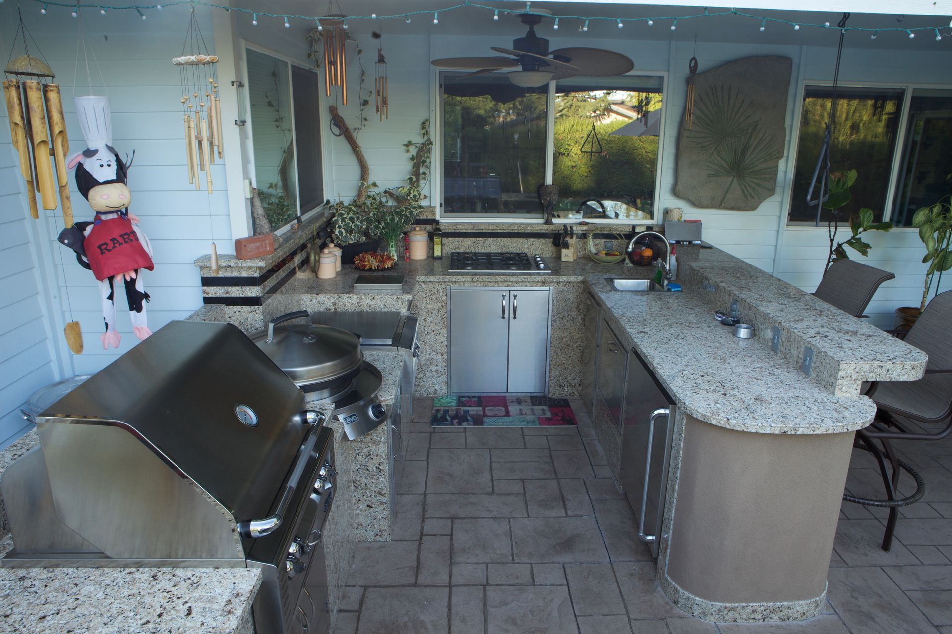 An outdoor kitchen with a stainless steel grill and granite counter tops