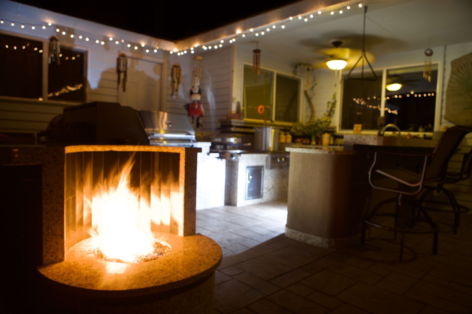 A fireplace is lit up in a kitchen at night