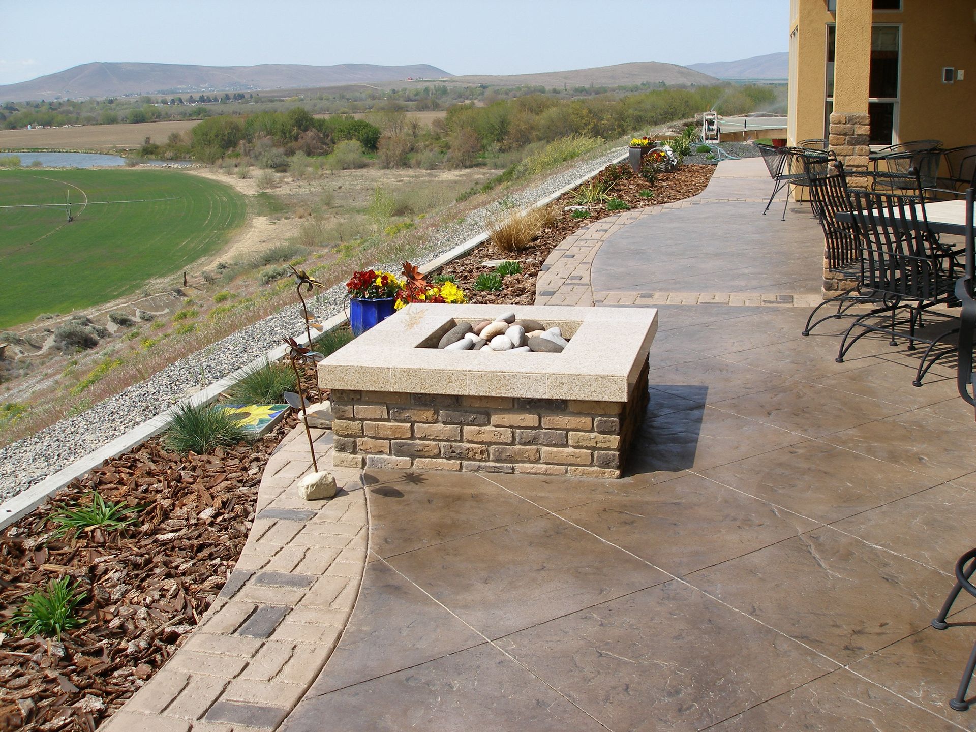 A fire pit on a patio with a view of a field