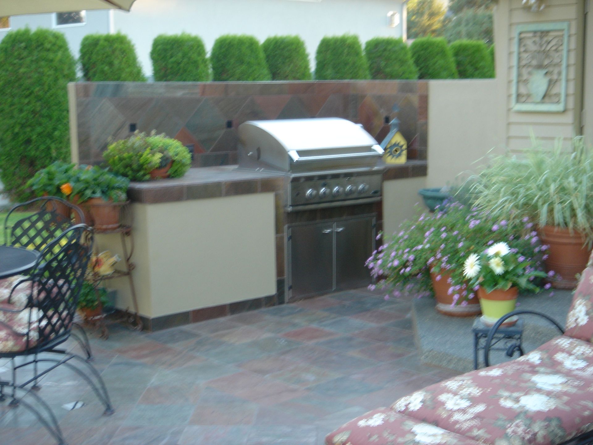 A patio with a grill and a table and chairs