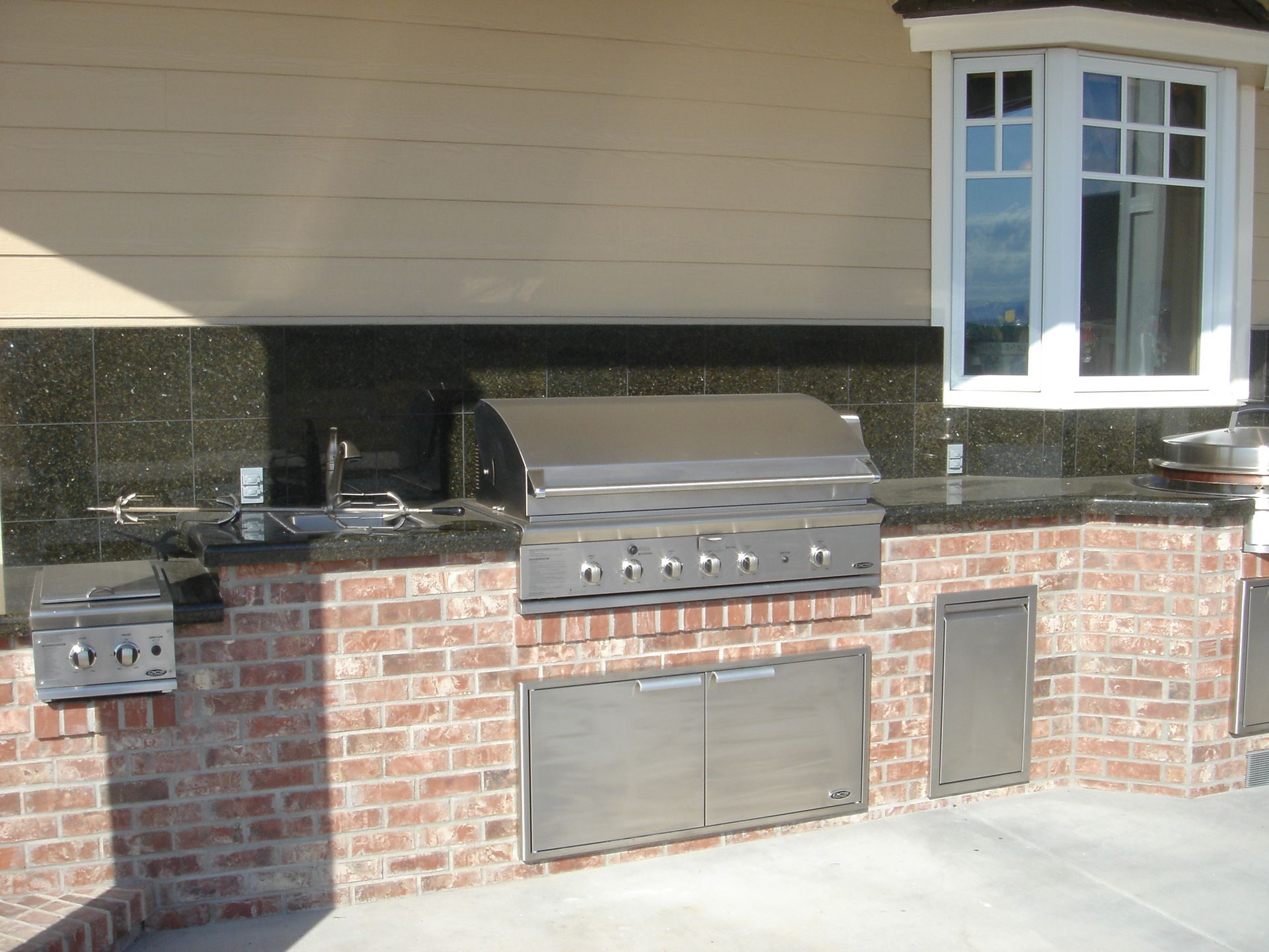 An outdoor kitchen with a grill and a window