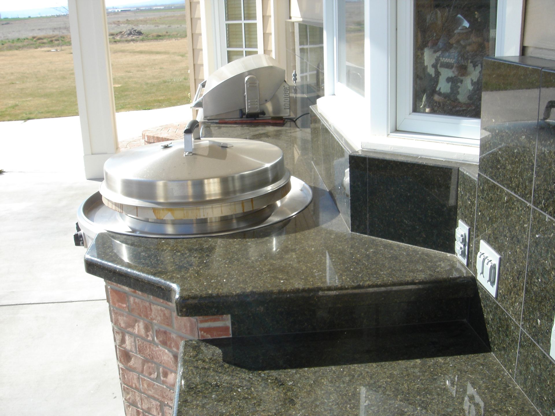 A kitchen with granite counter tops and a stainless steel grill