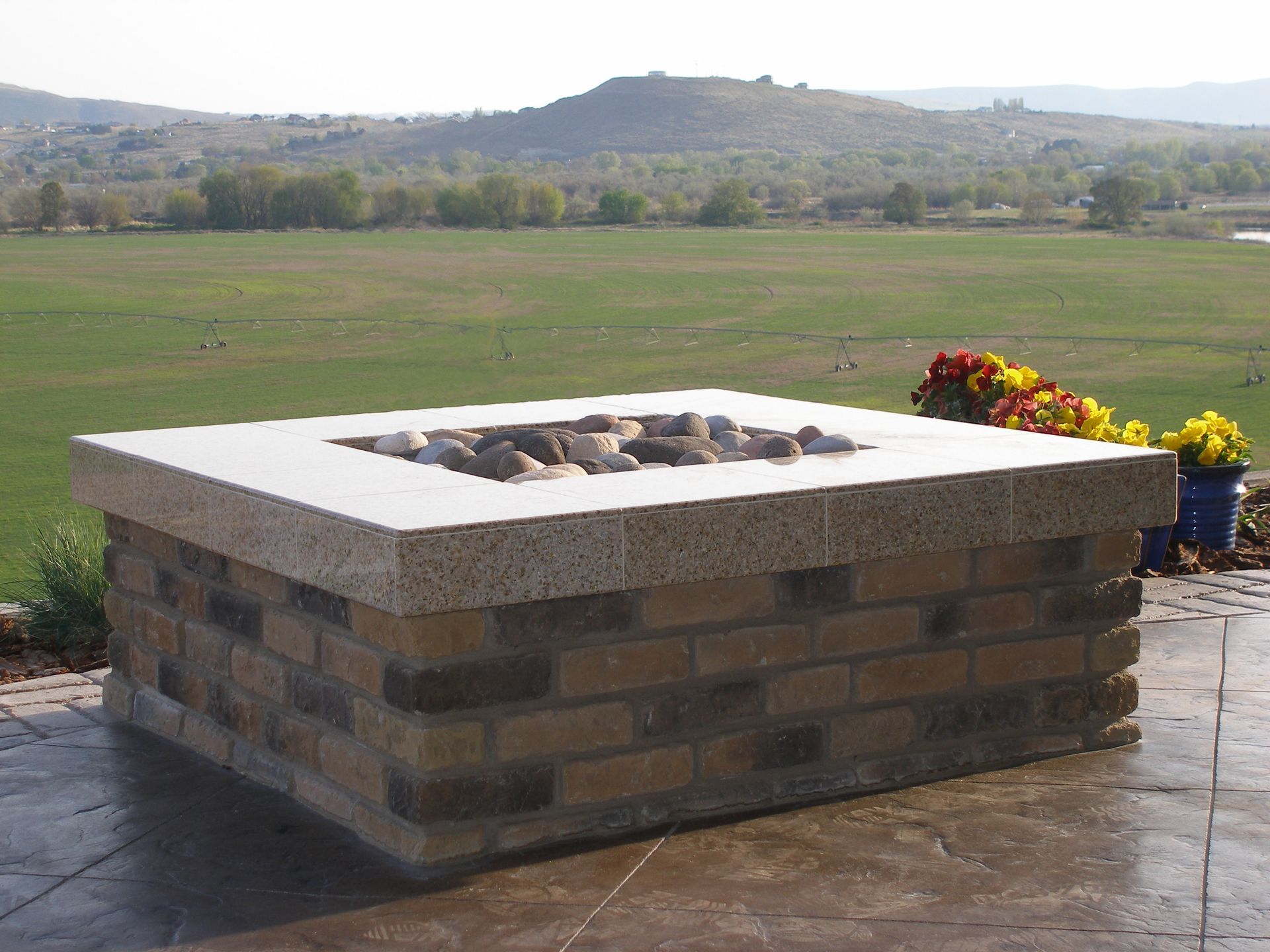 A fire pit with a view of a field in the background