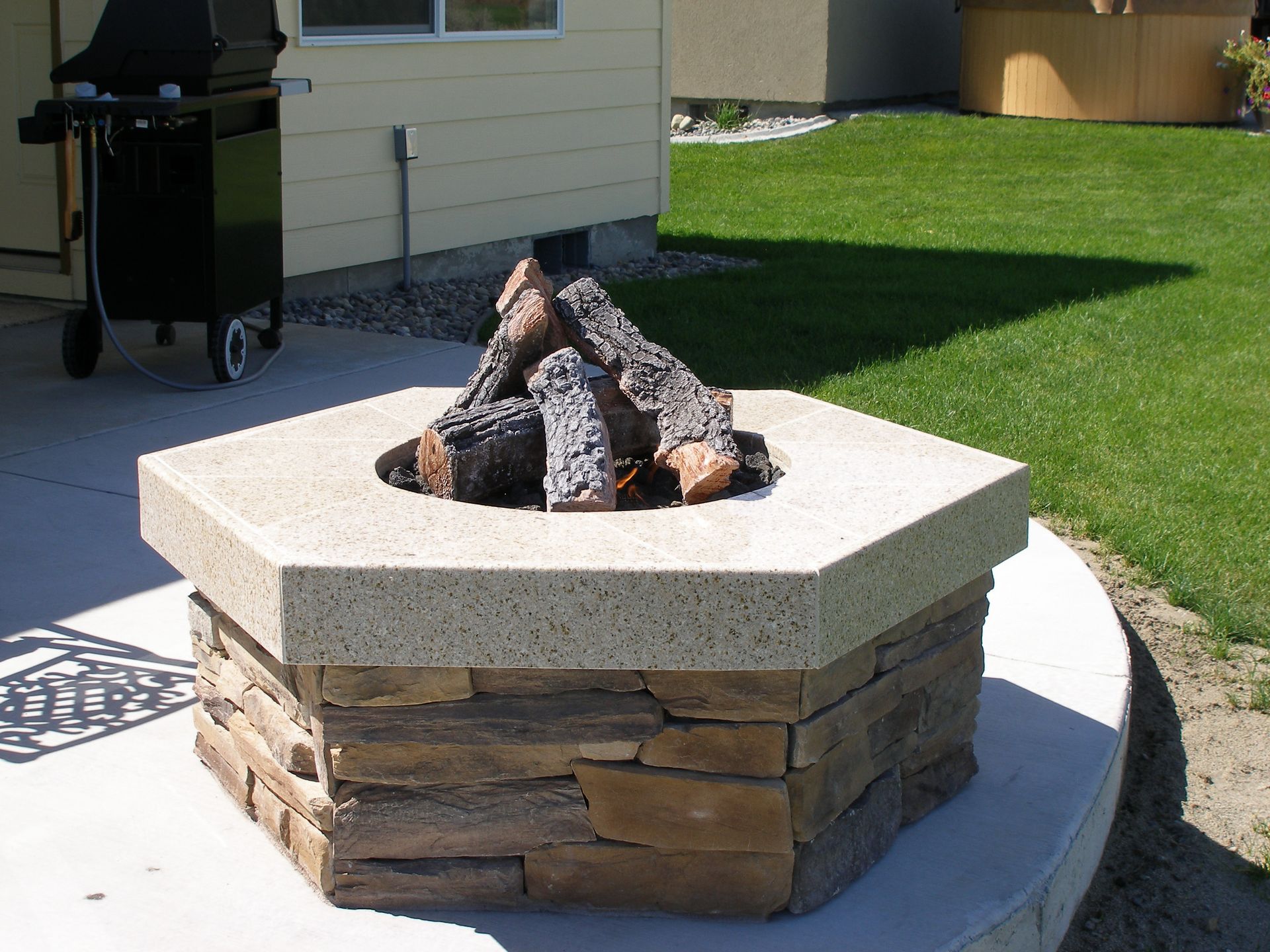 A fire pit with a grill in the background