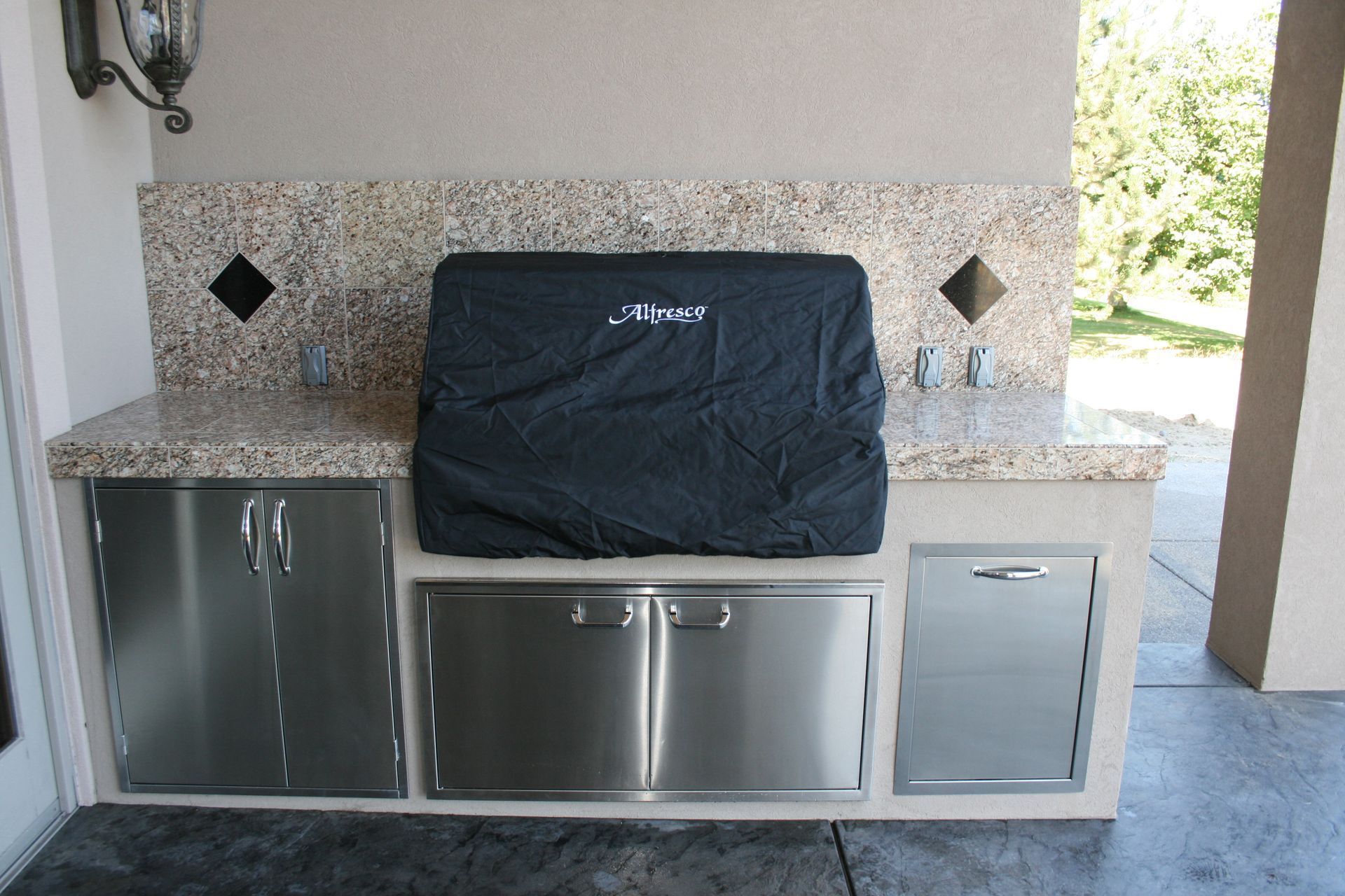 A stainless steel grill with a black cover on it