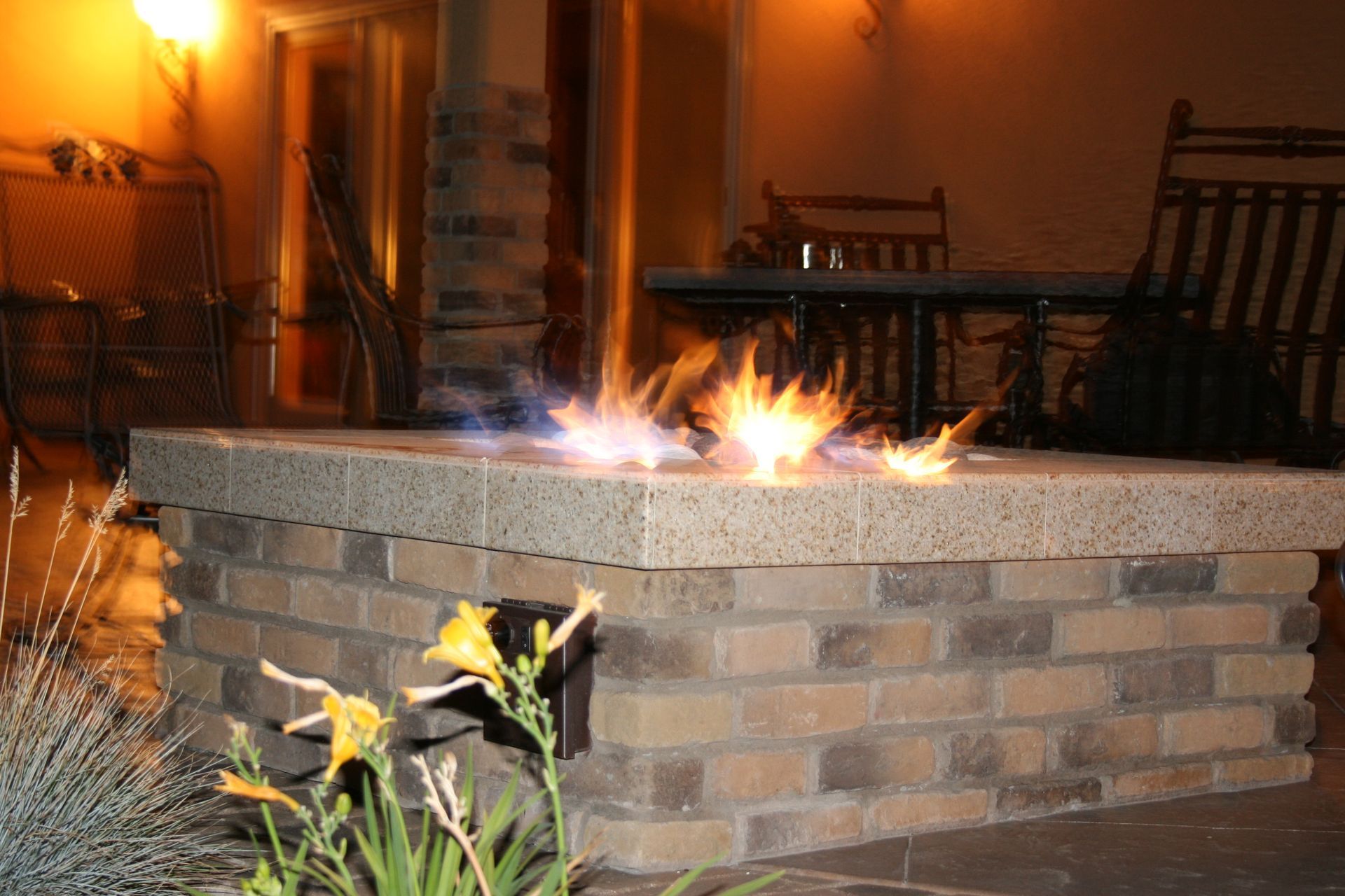 A fire pit made of bricks is lit up at night