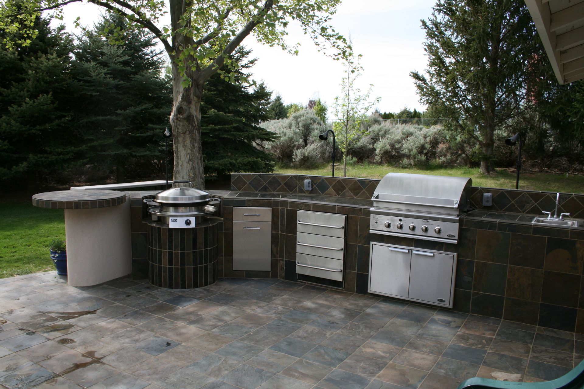 An outdoor kitchen with a grill and a sink
