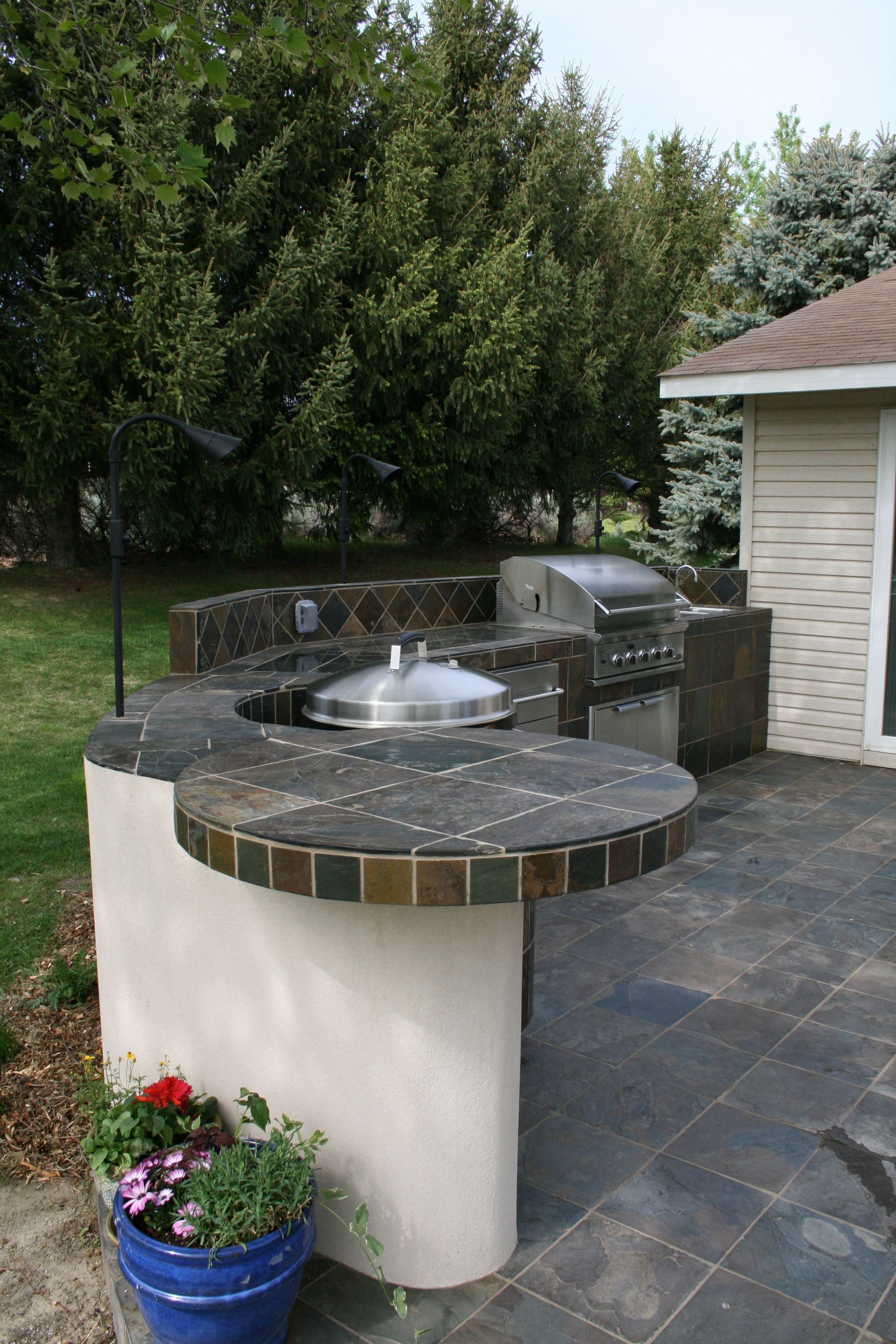 A patio with a grill and a blue pot of flowers