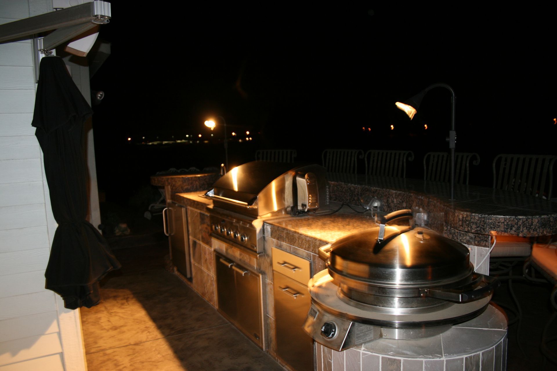 An outdoor kitchen with a grill and stove at night