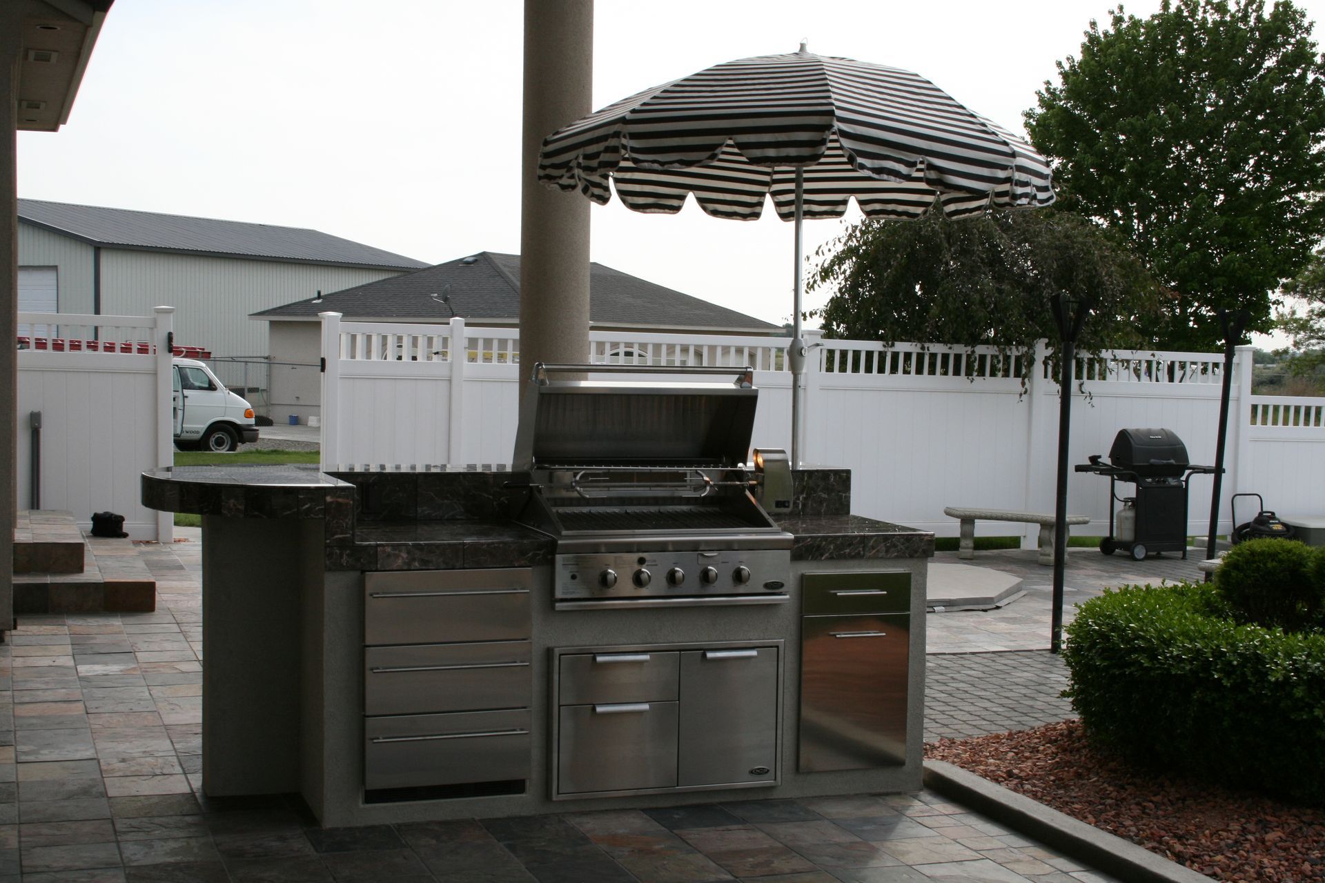An outdoor kitchen with a striped umbrella over it