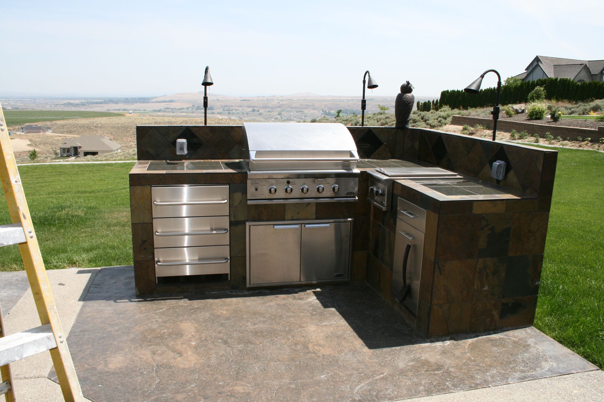 A large outdoor kitchen with a grill and a ladder