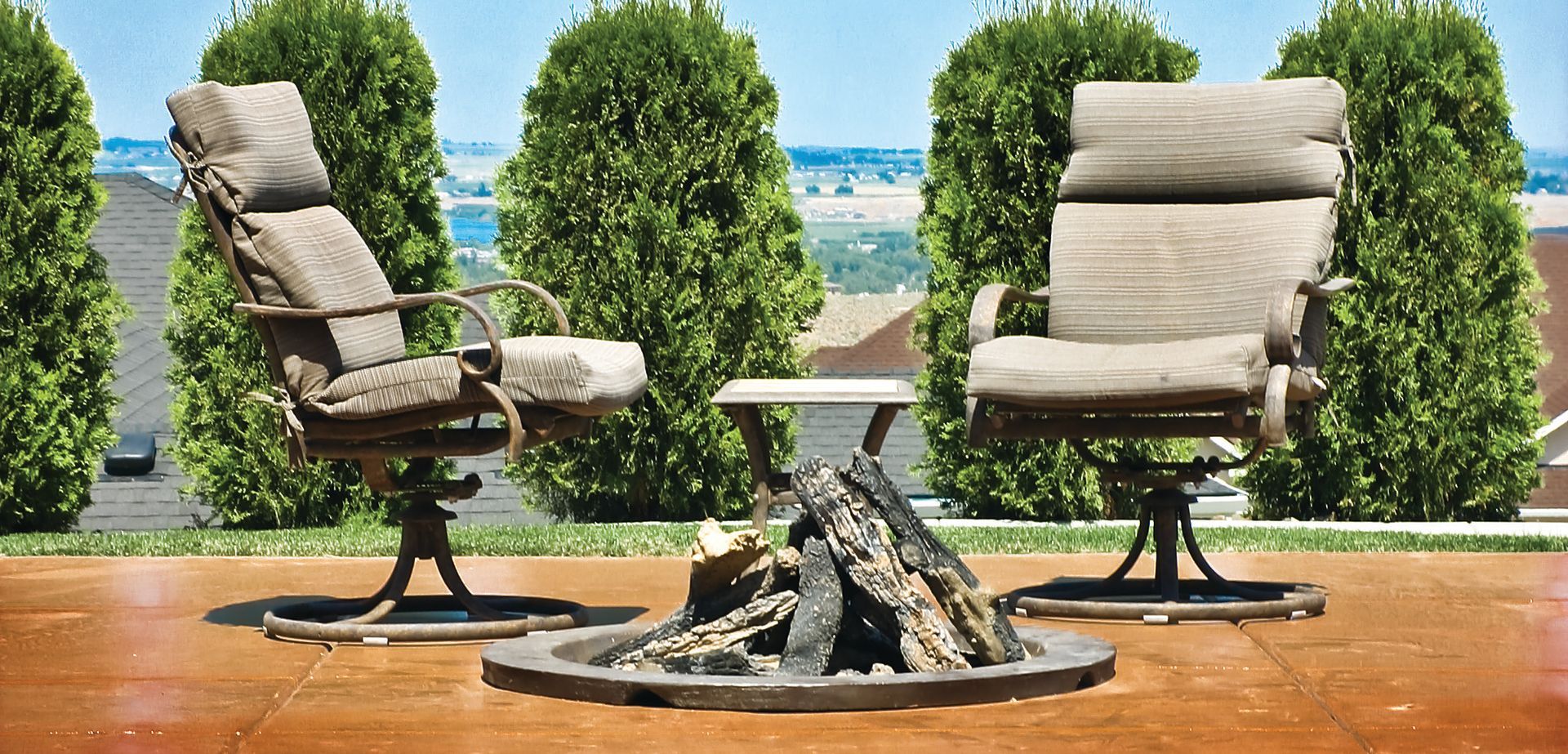 Two chairs are sitting next to a fire pit on a patio.