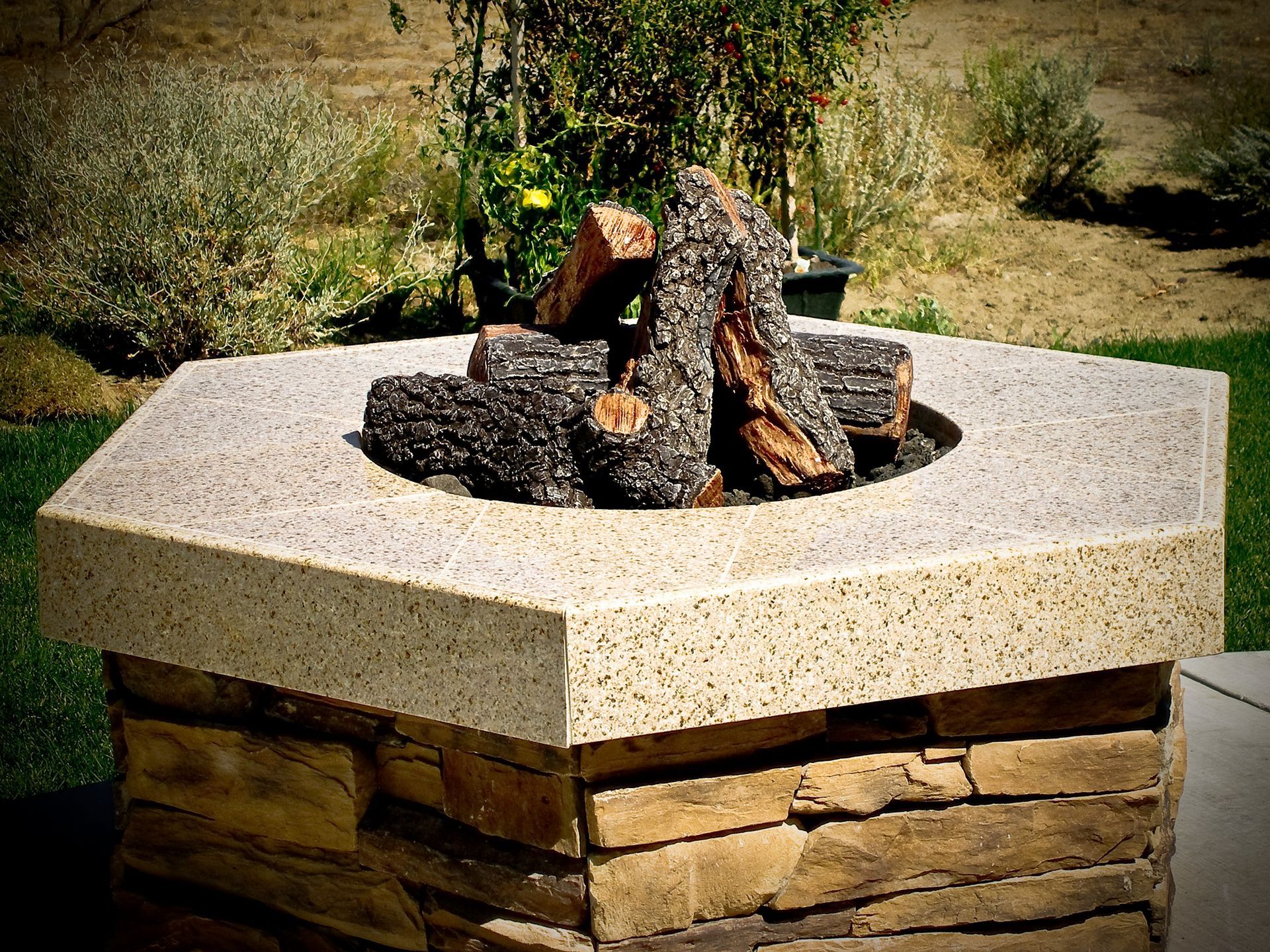 A fire pit made of stone and concrete with logs in it