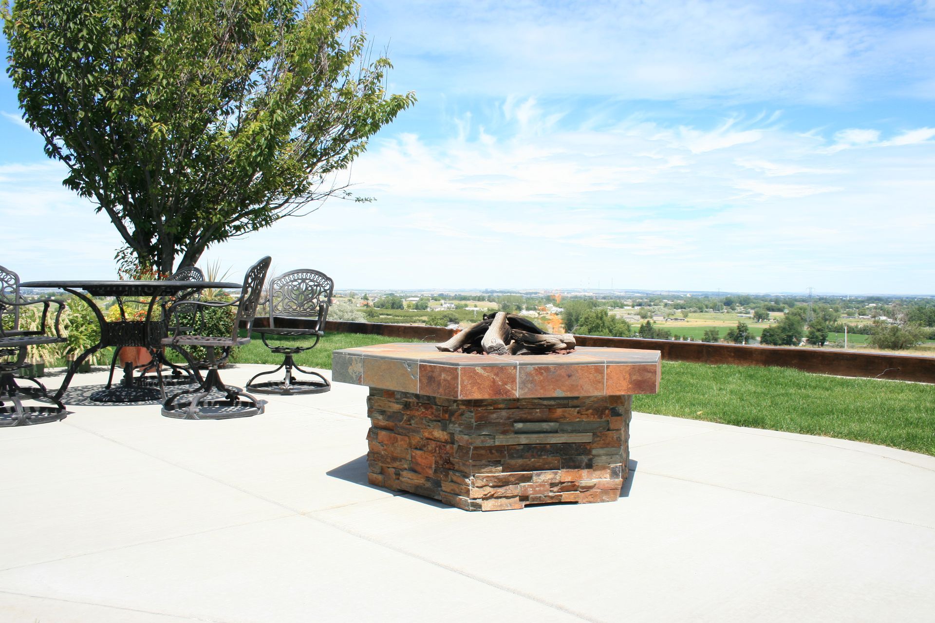 A fire pit is sitting on a patio next to a table and chairs.