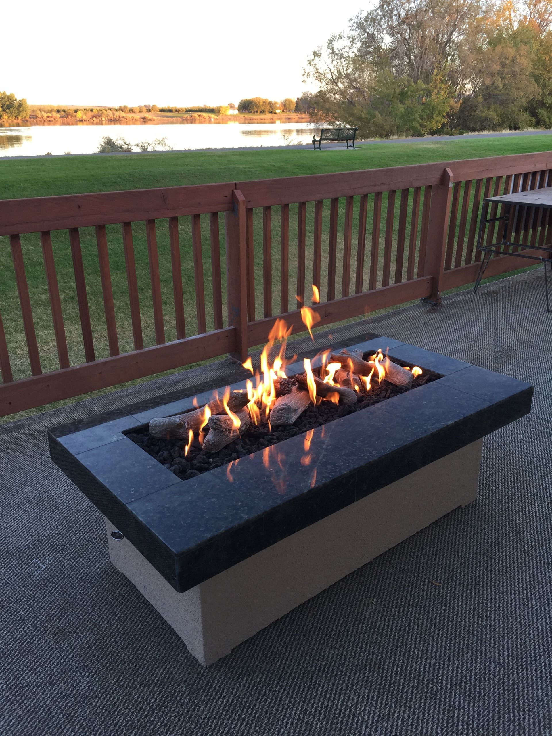 A fire pit is sitting on a patio next to a wooden fence.