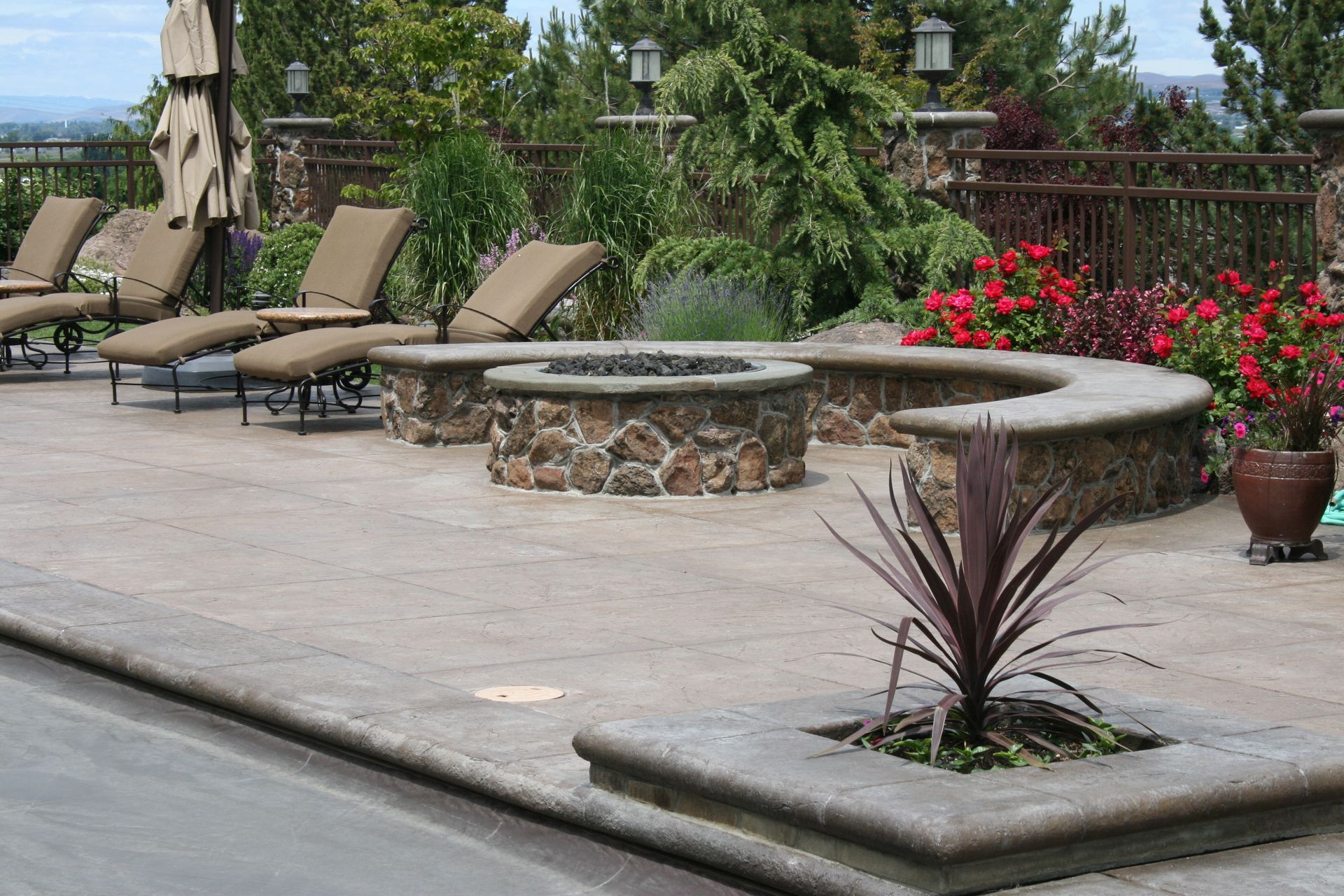 A patio with a fire pit and lounge chairs