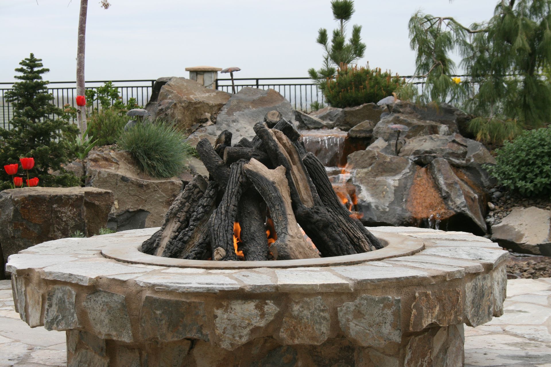 A fire pit is surrounded by rocks and a waterfall.