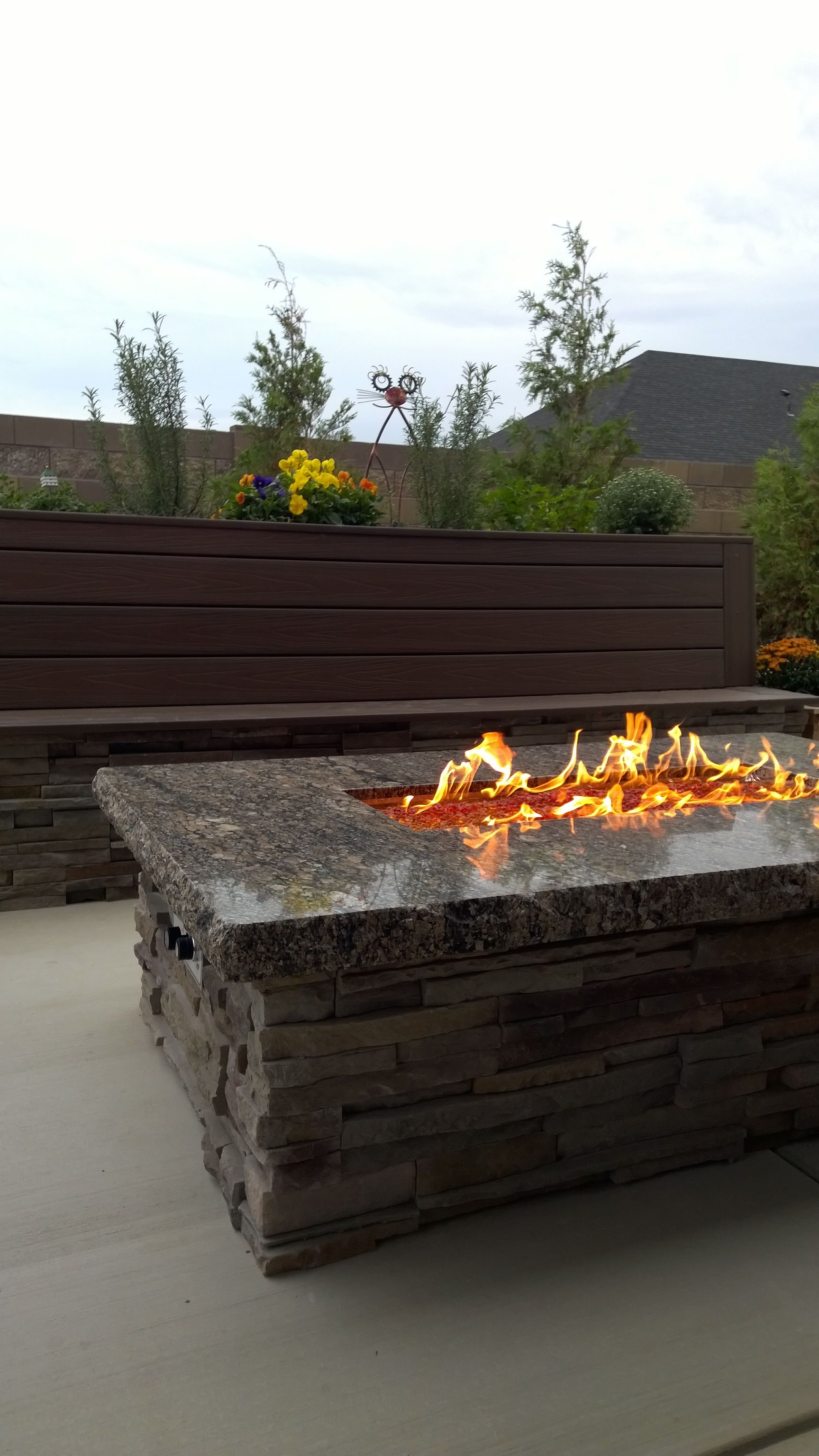 A fire pit is sitting on a patio next to a bench.