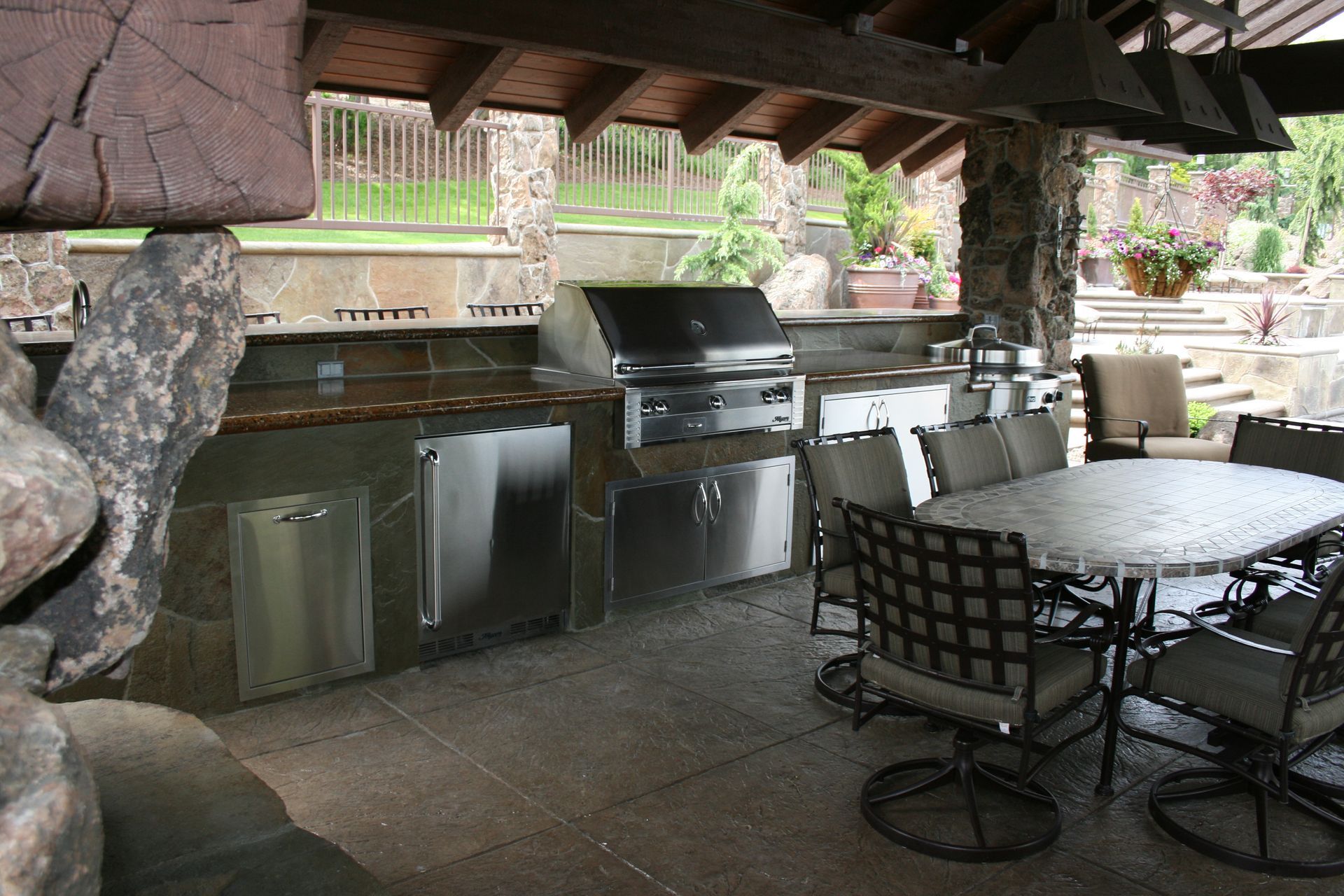 An outdoor kitchen with a table and chairs and a grill