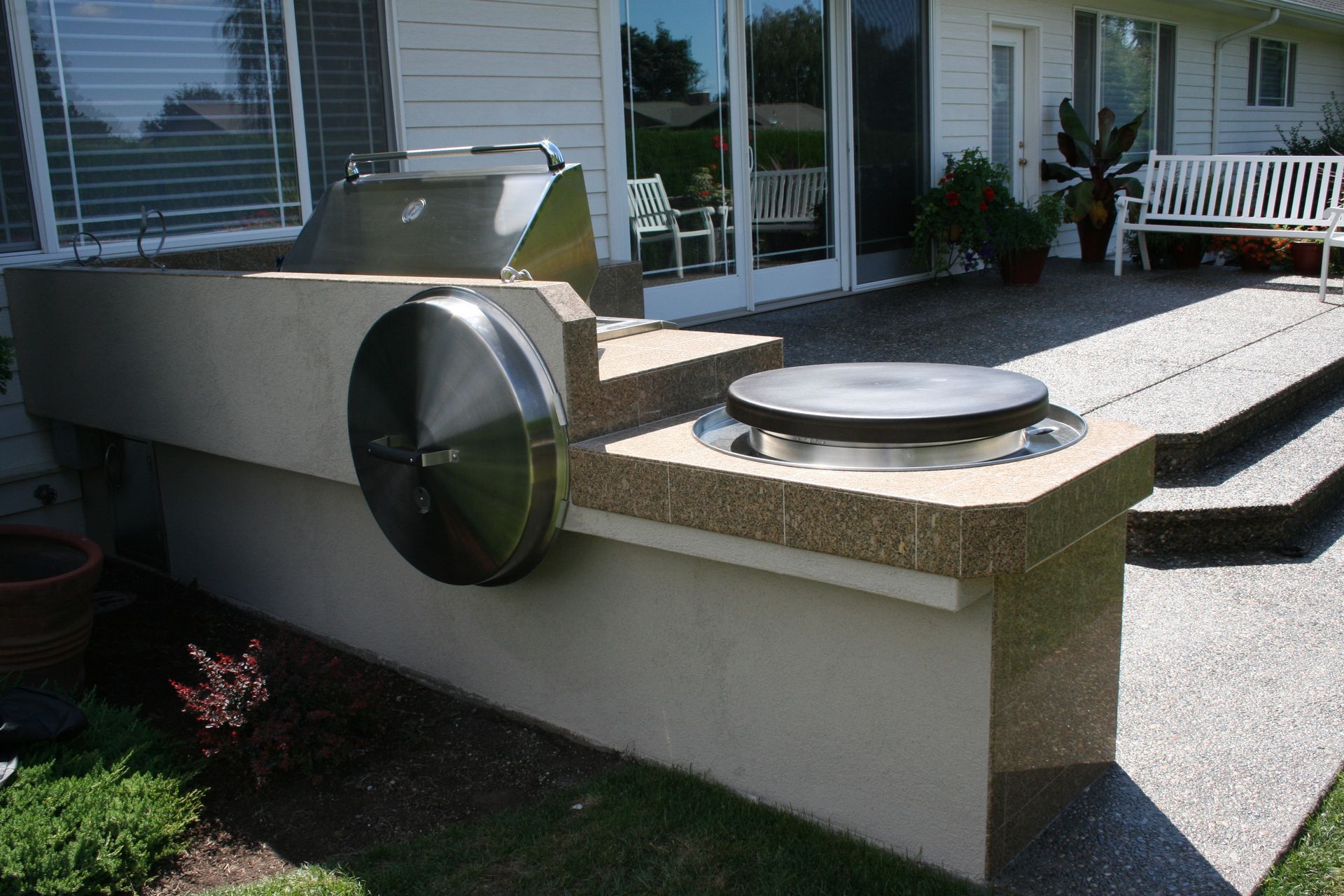 A stainless steel grill is sitting on the side of a house