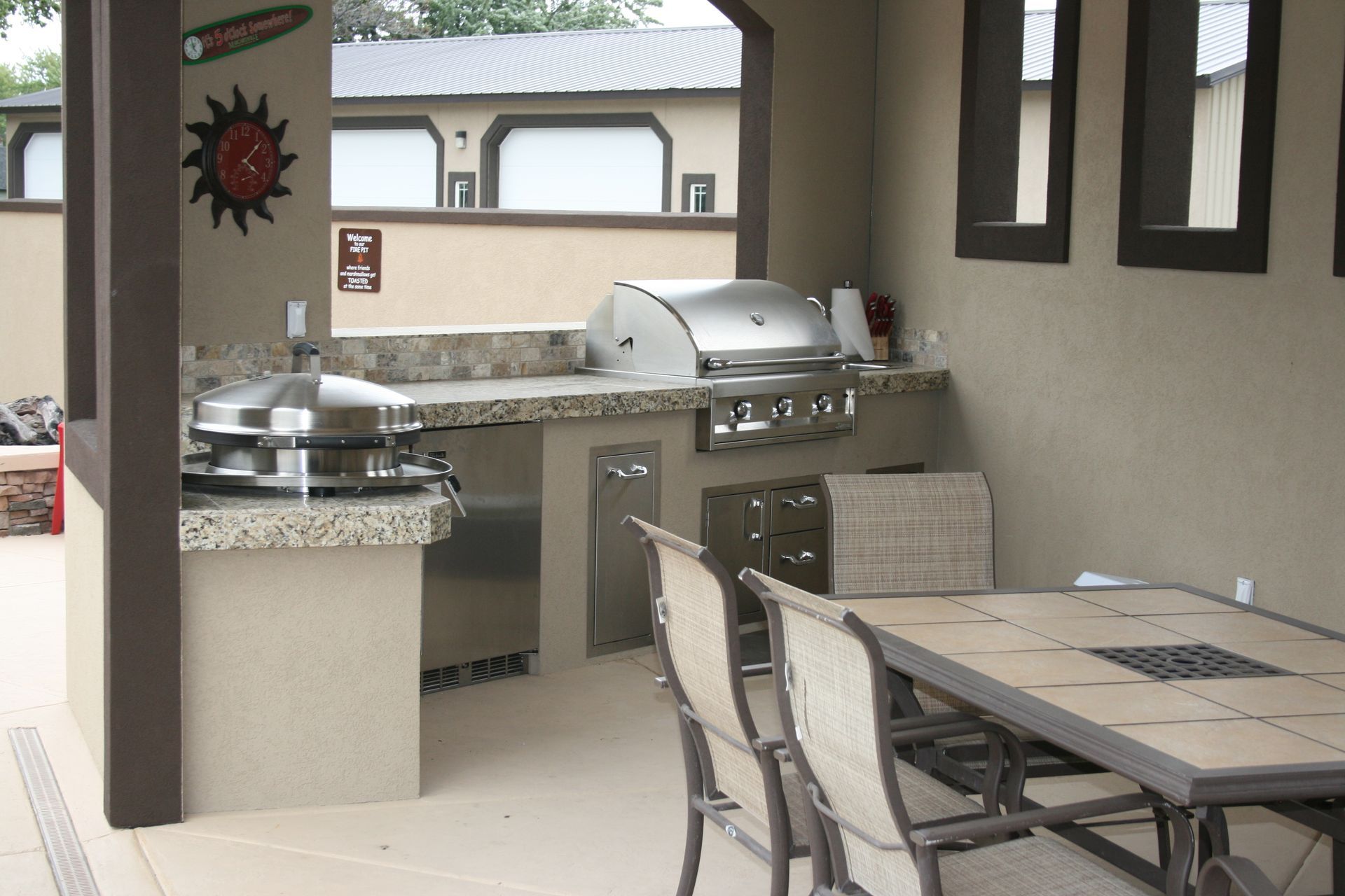 An outdoor kitchen with a table and chairs and a grill