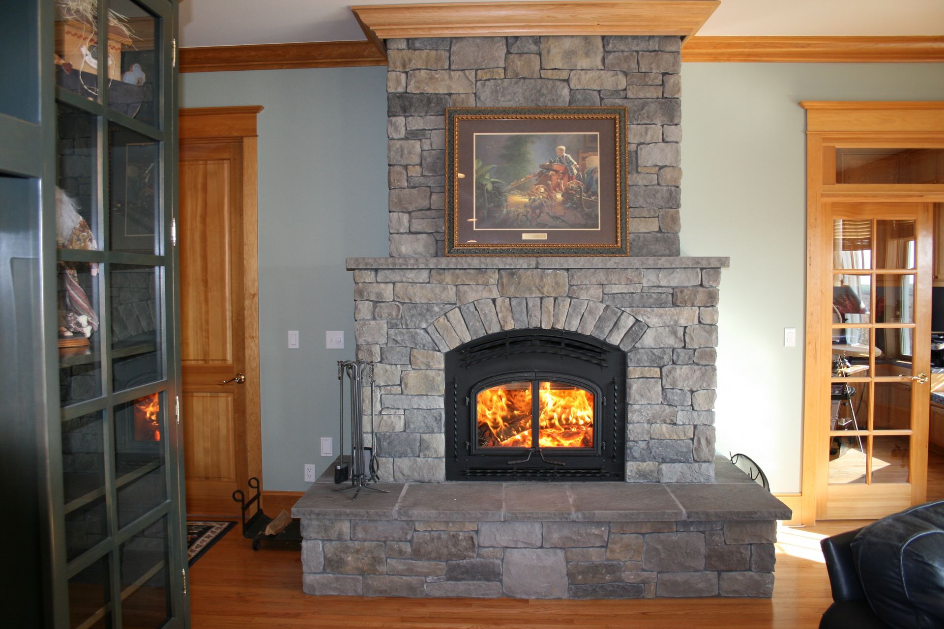 A living room with a stone fireplace and a painting on the wall above it
