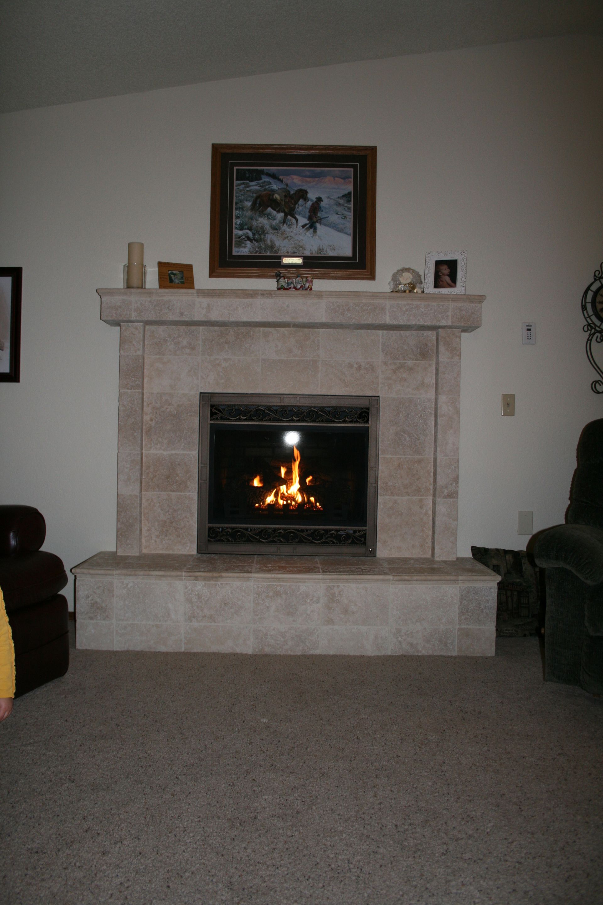 A living room with a fireplace and a picture on the wall above it