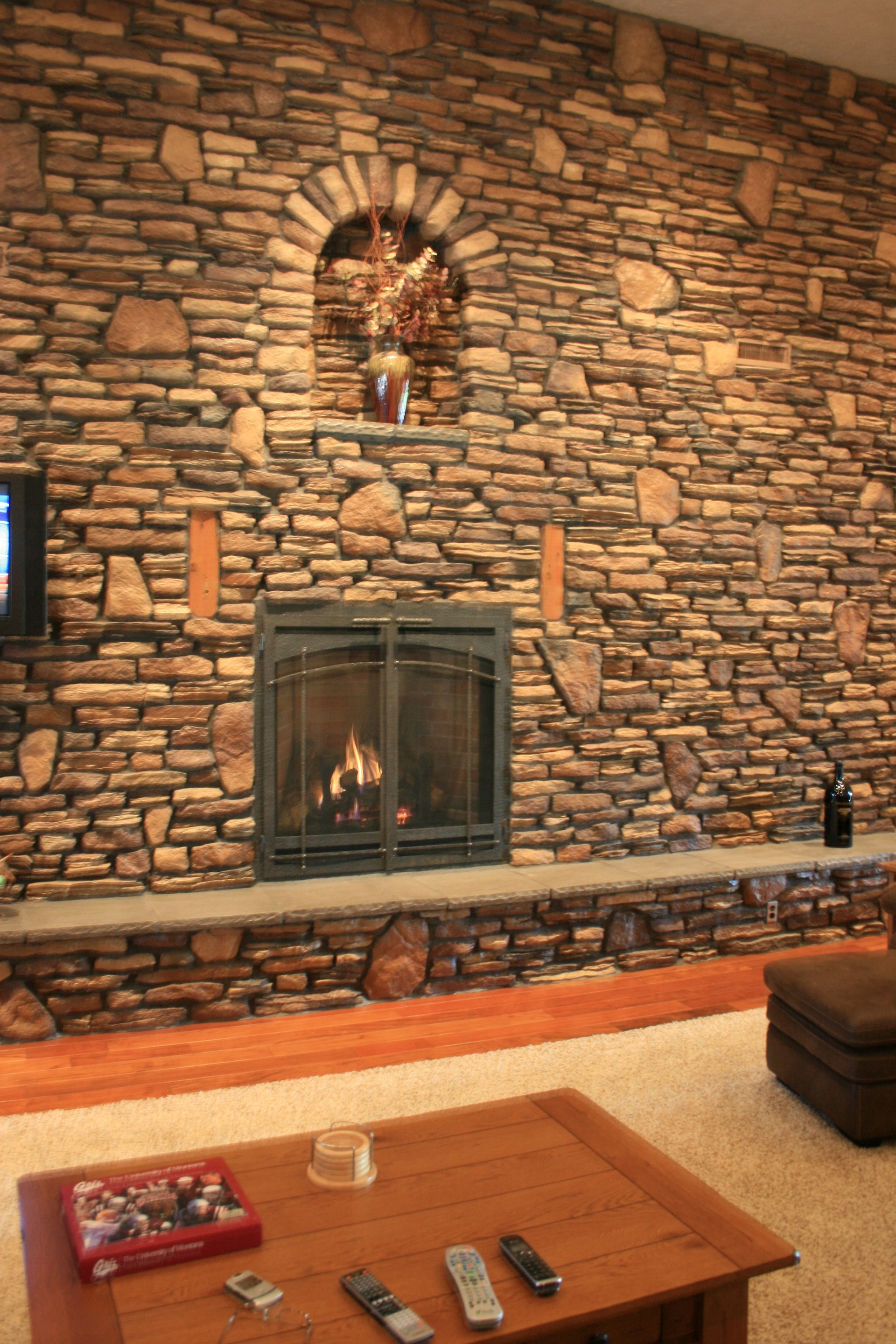 A living room with a large stone wall and a fireplace