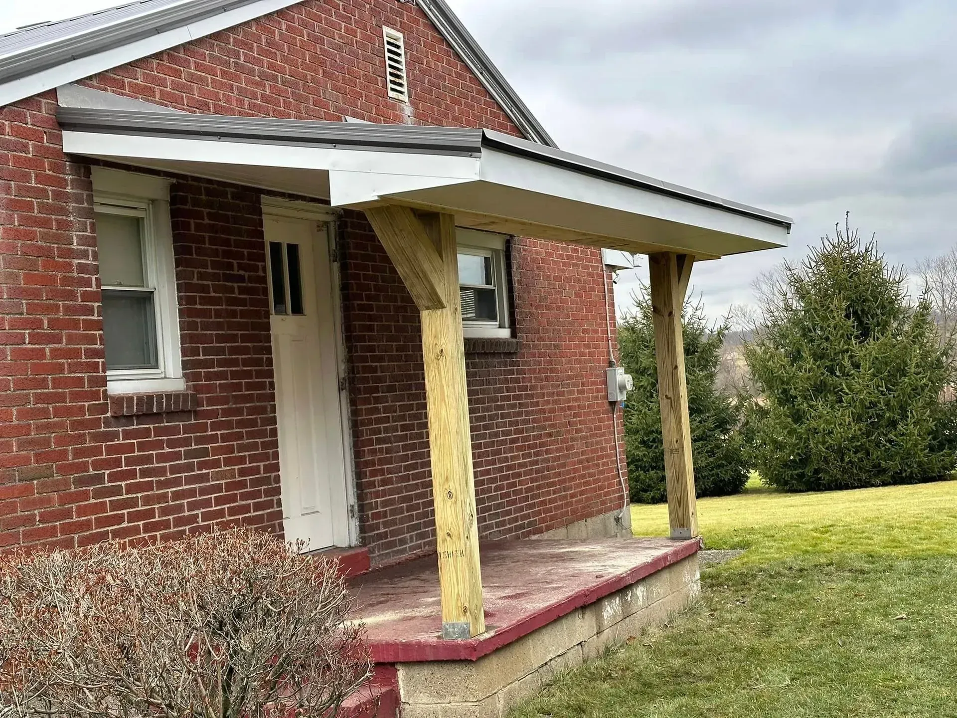 A small brick house with a porch on the side of it.
