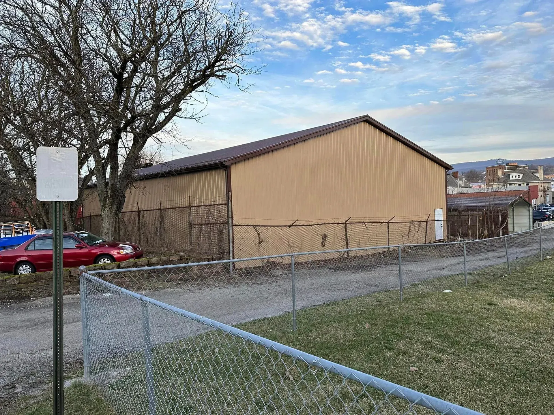 A large building is behind a chain link fence in a parking lot.