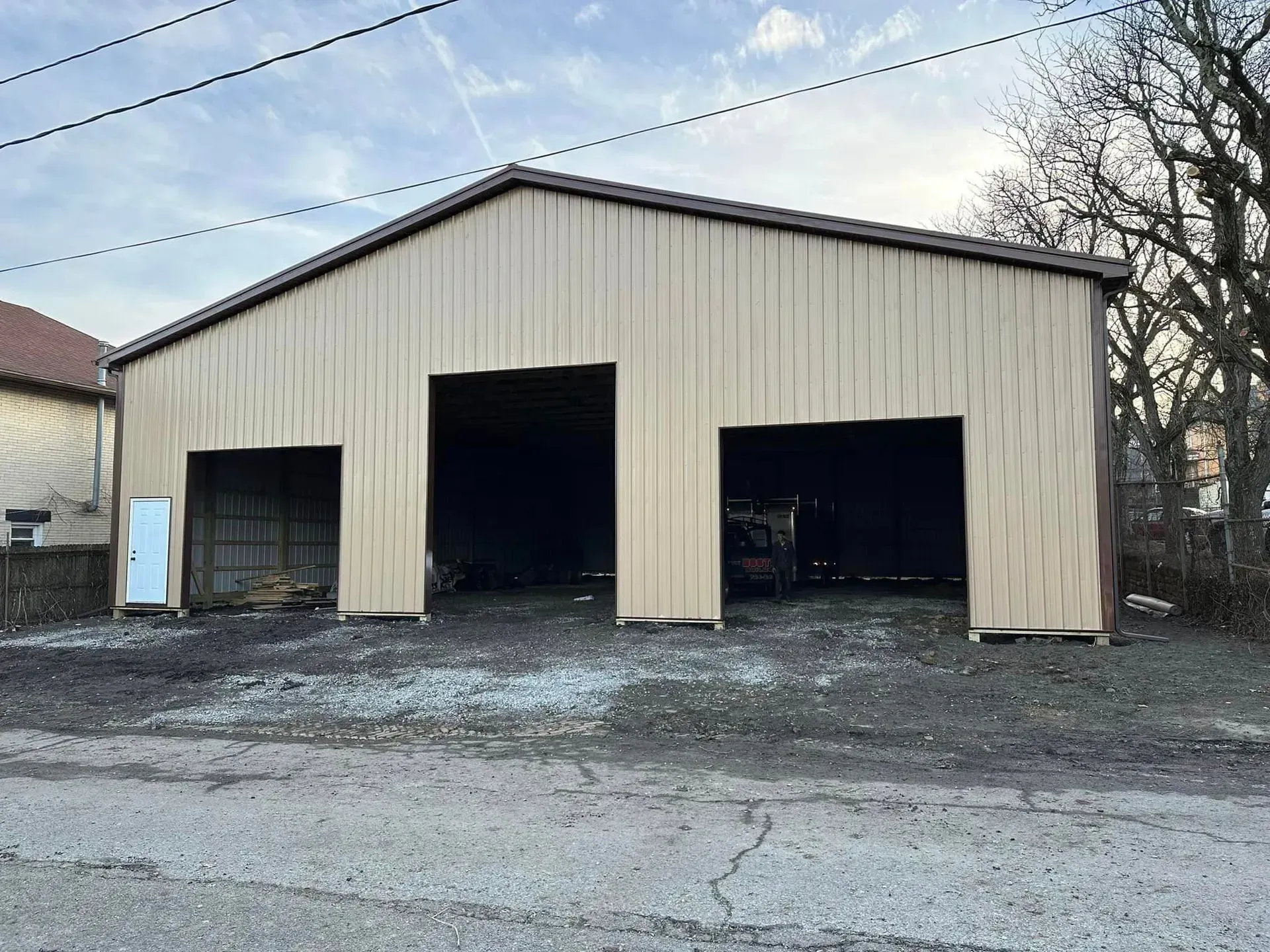 A large metal building with two doors is sitting on the side of the road.