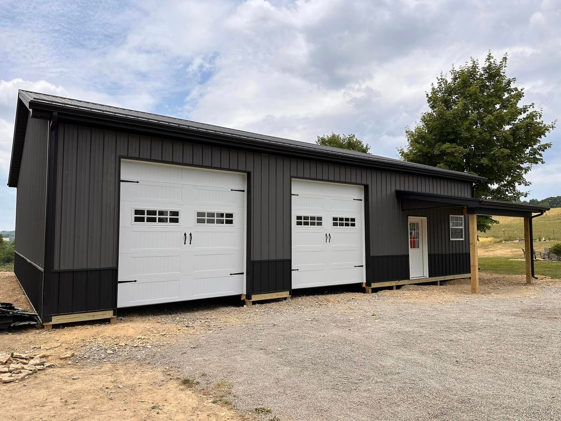 A black and white garage with two garage doors and a porch.