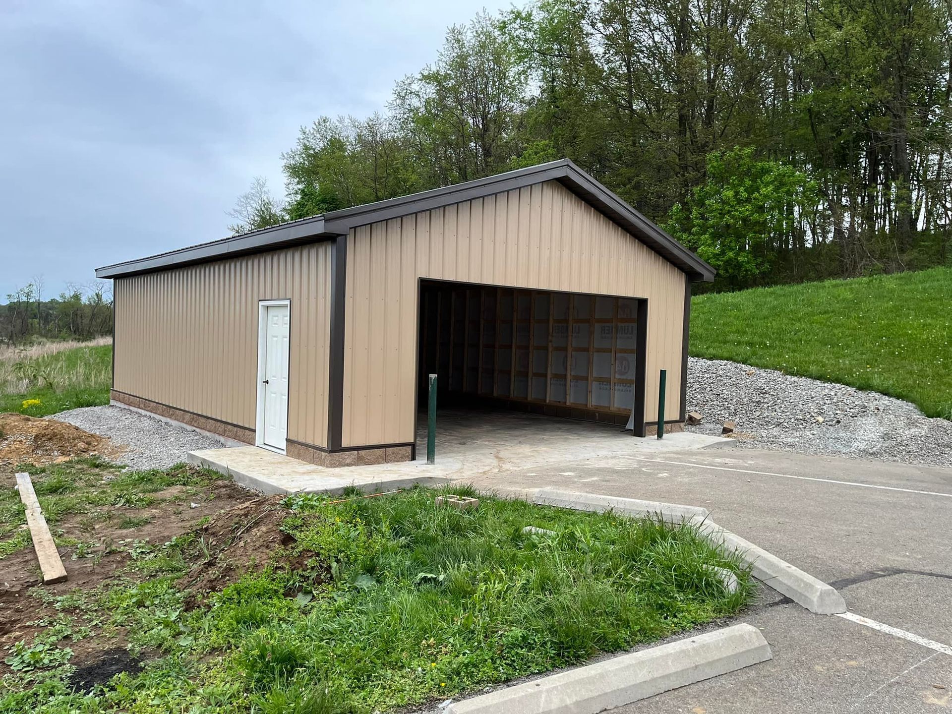 A garage is sitting on the side of a road next to a grassy hill.