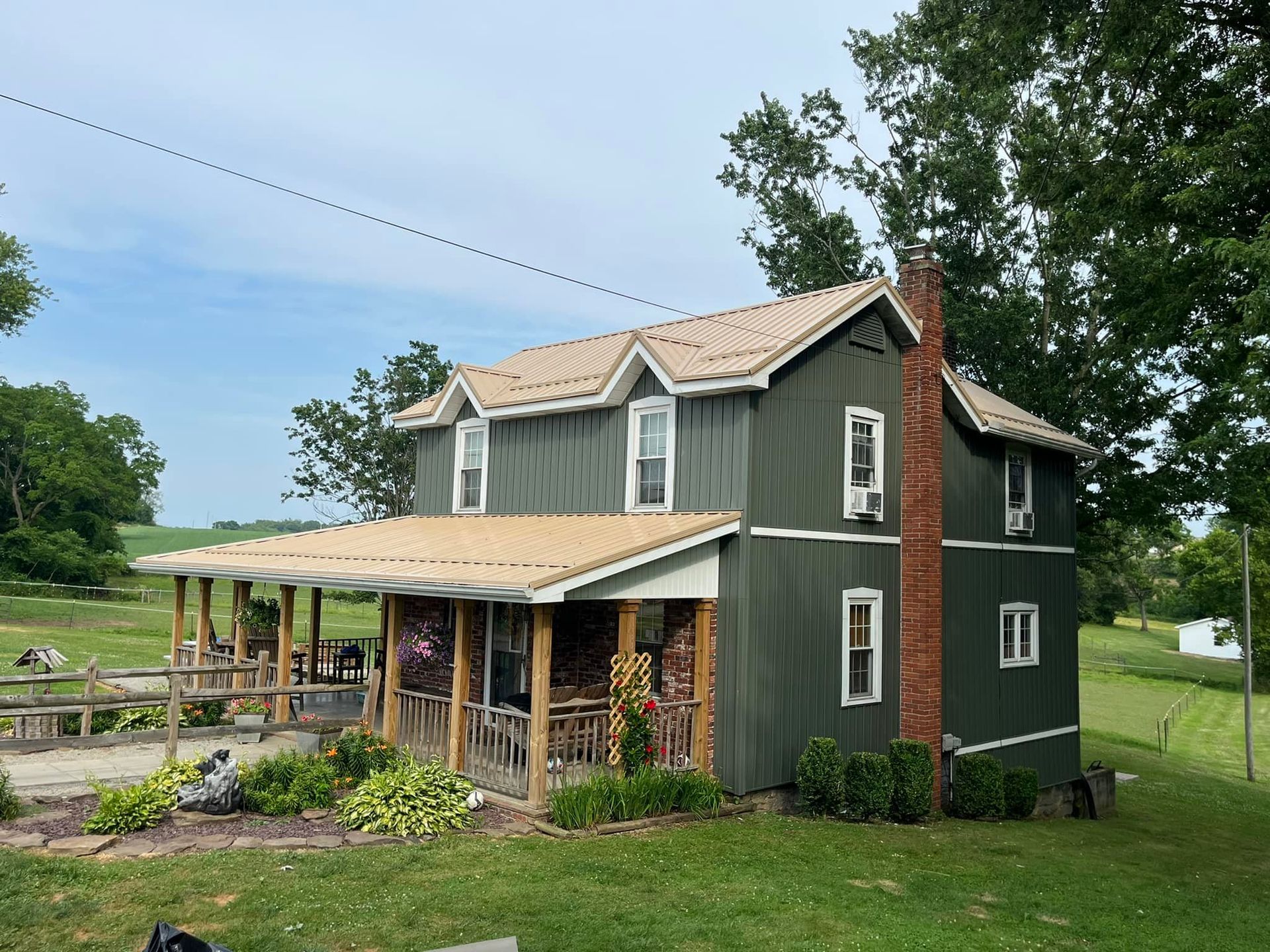 A green house with a porch and a chimney