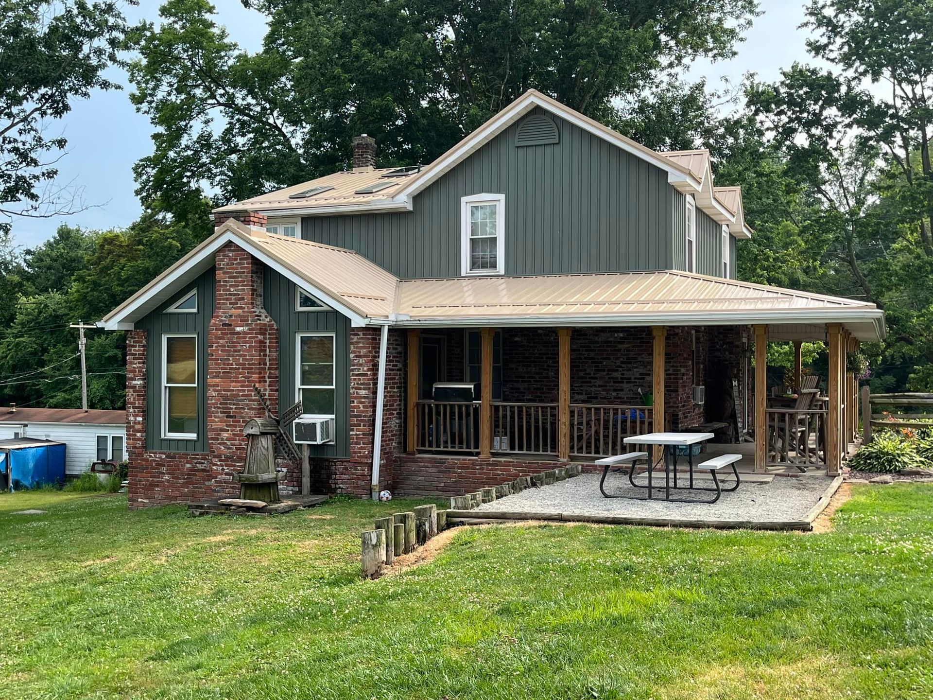 A large house with a porch and a picnic table in front of it.