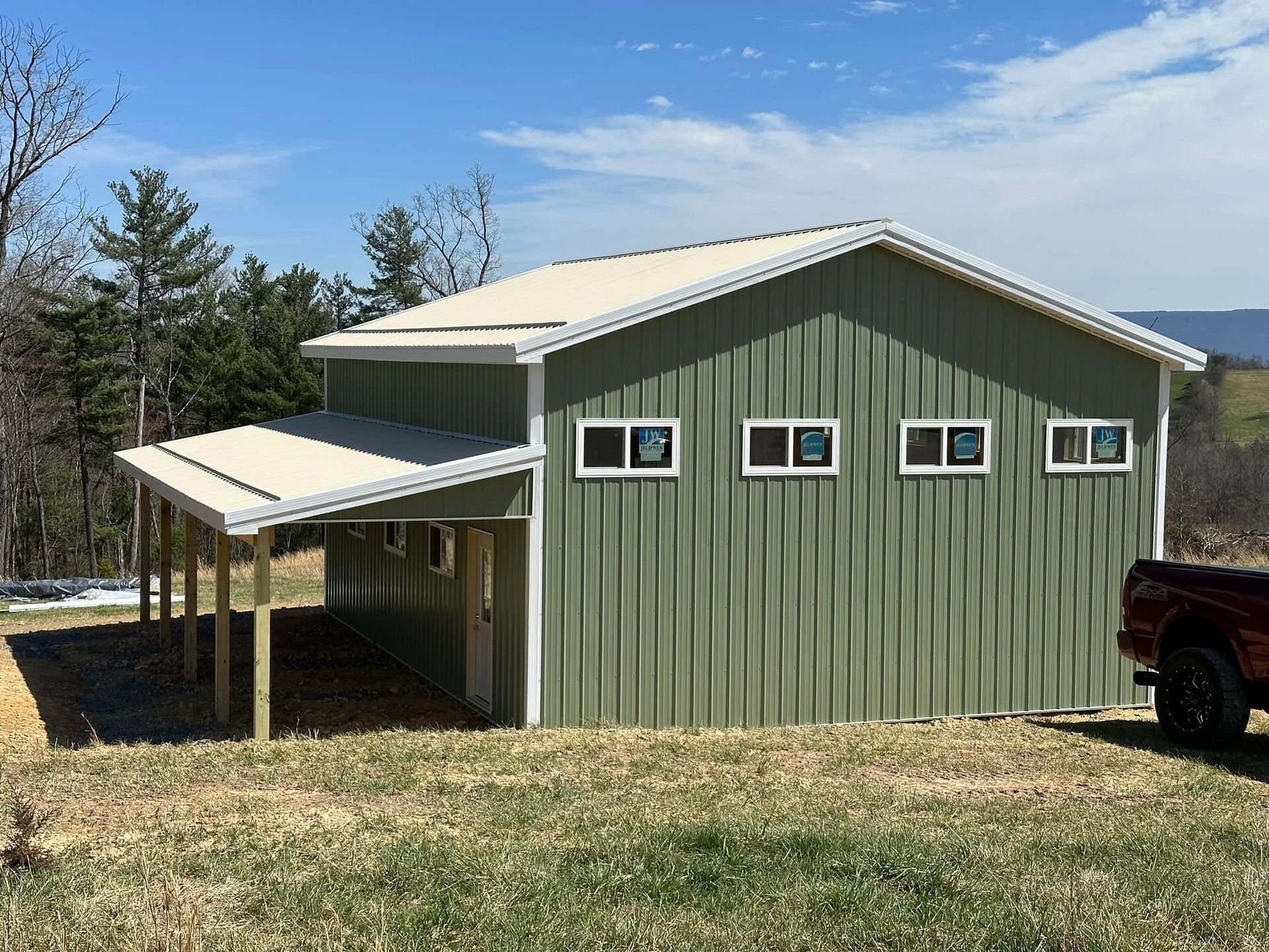 A green building with a white roof and a truck parked in front of it.