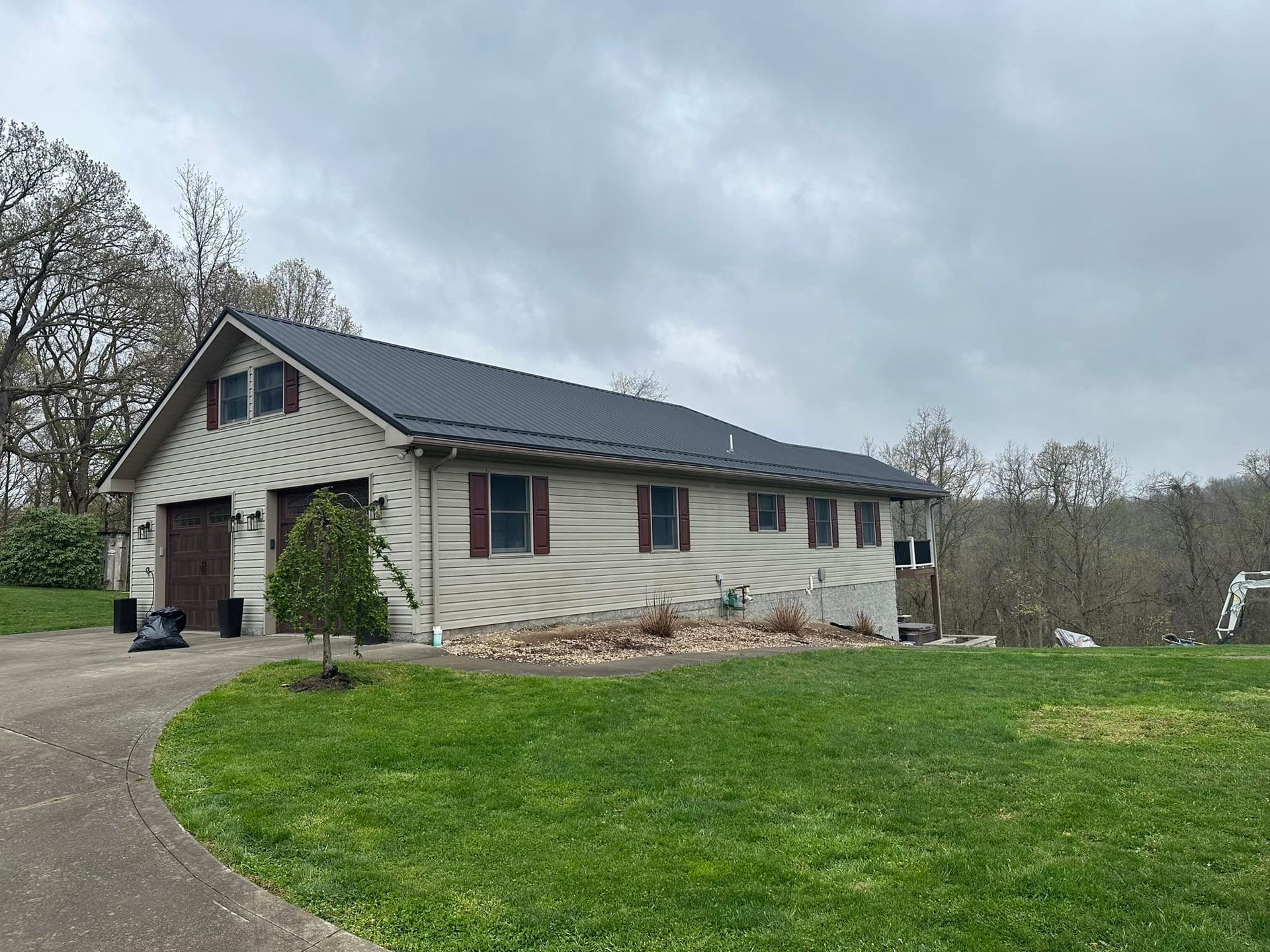 A large white house with a black roof is sitting on top of a lush green field.