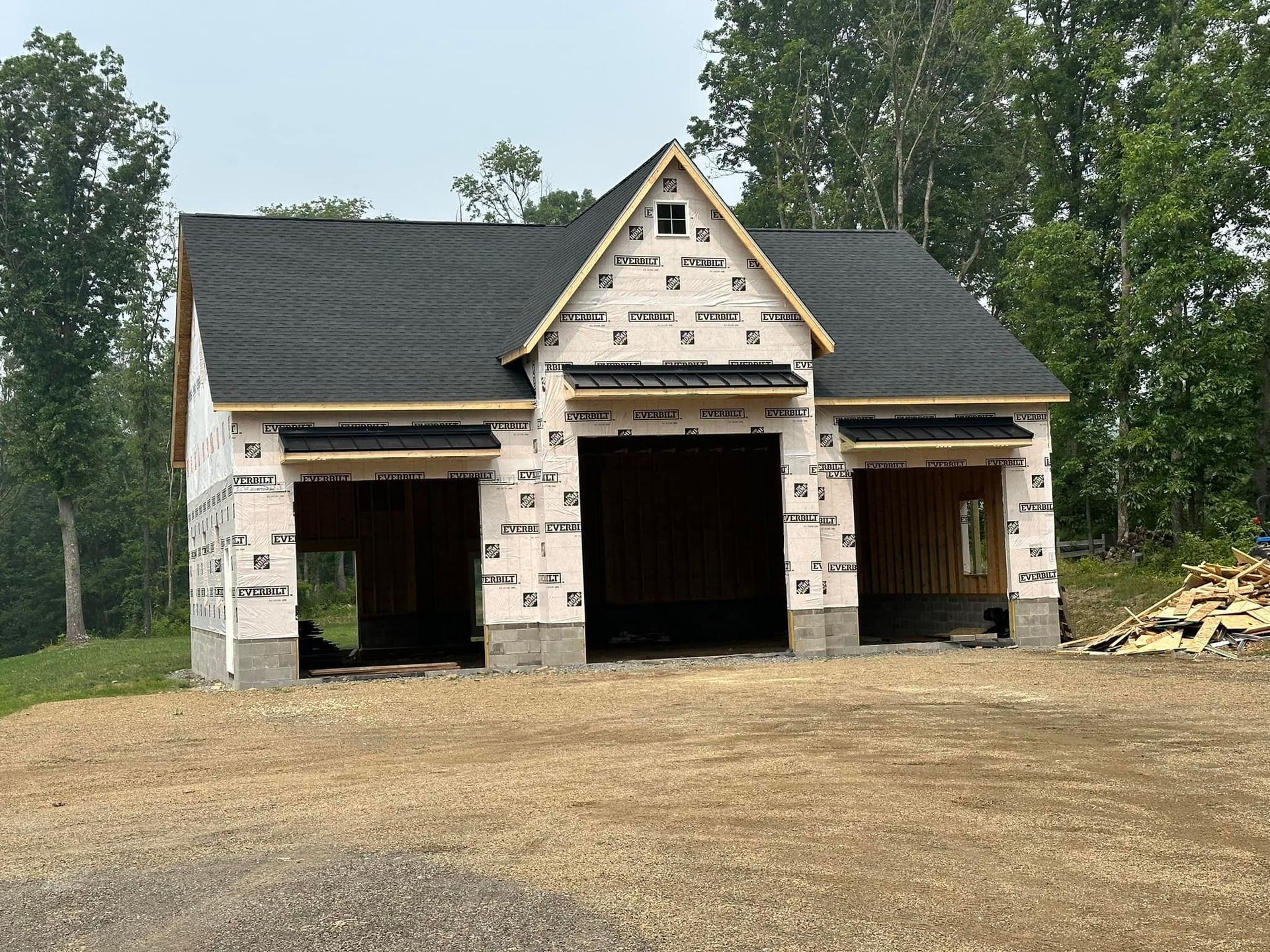 A white house with a black roof is under construction.