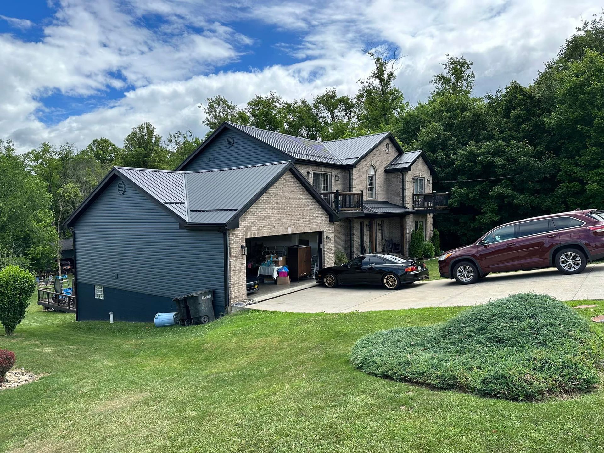 A large house with a garage and two cars parked in front of it.