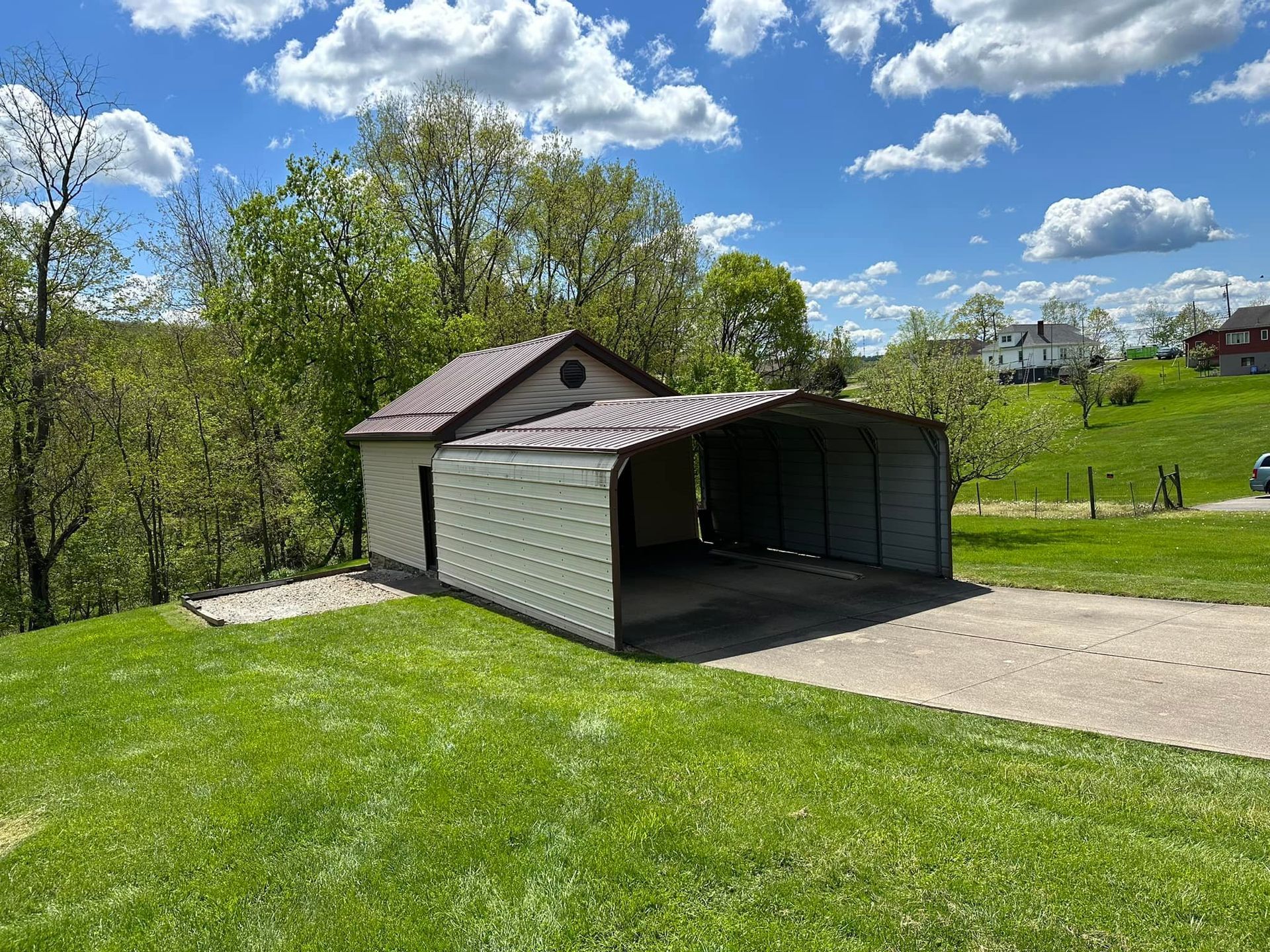 A metal garage is sitting in the middle of a lush green field.