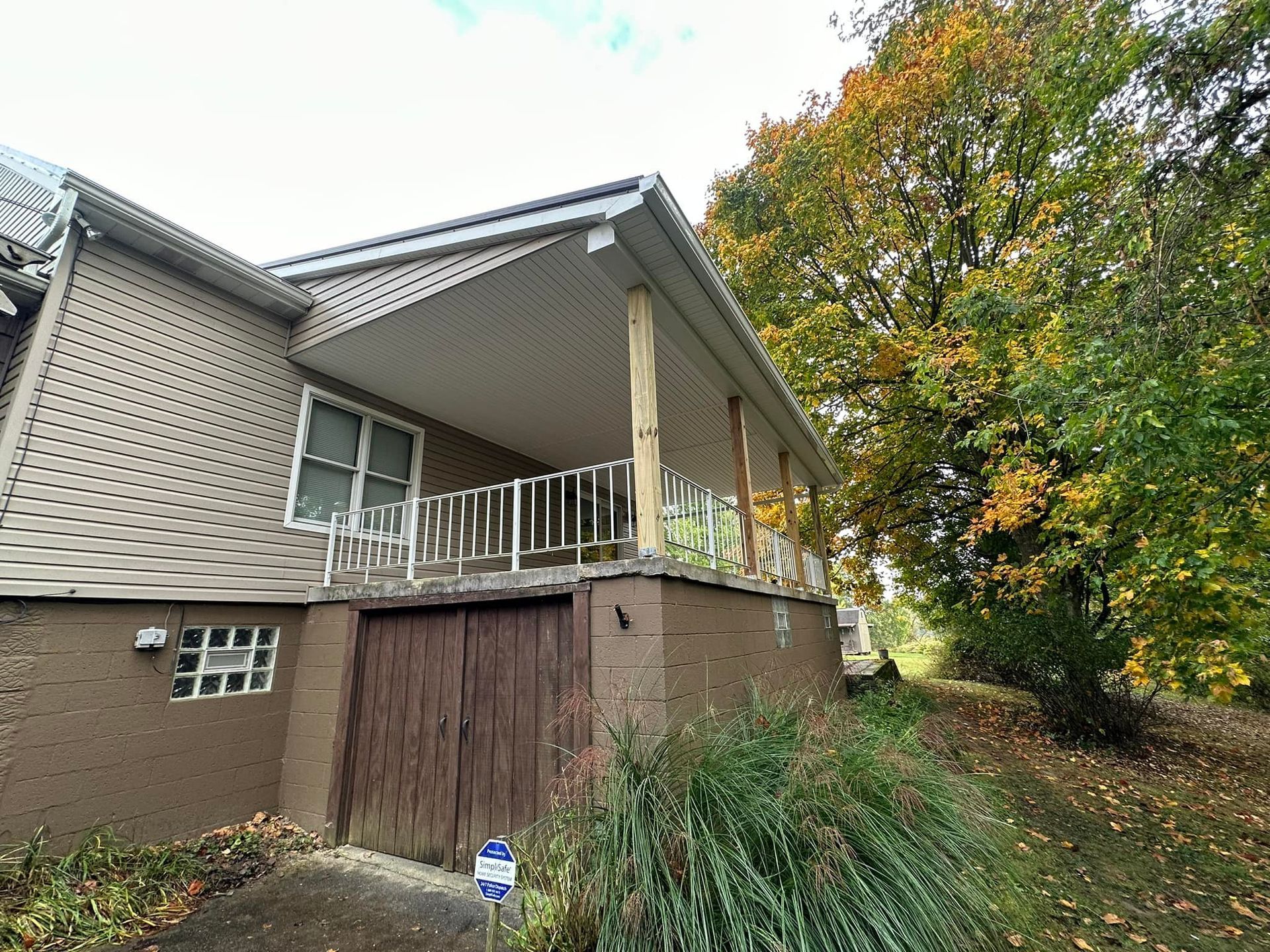 A wooden porch is sitting in front of a brick house.
