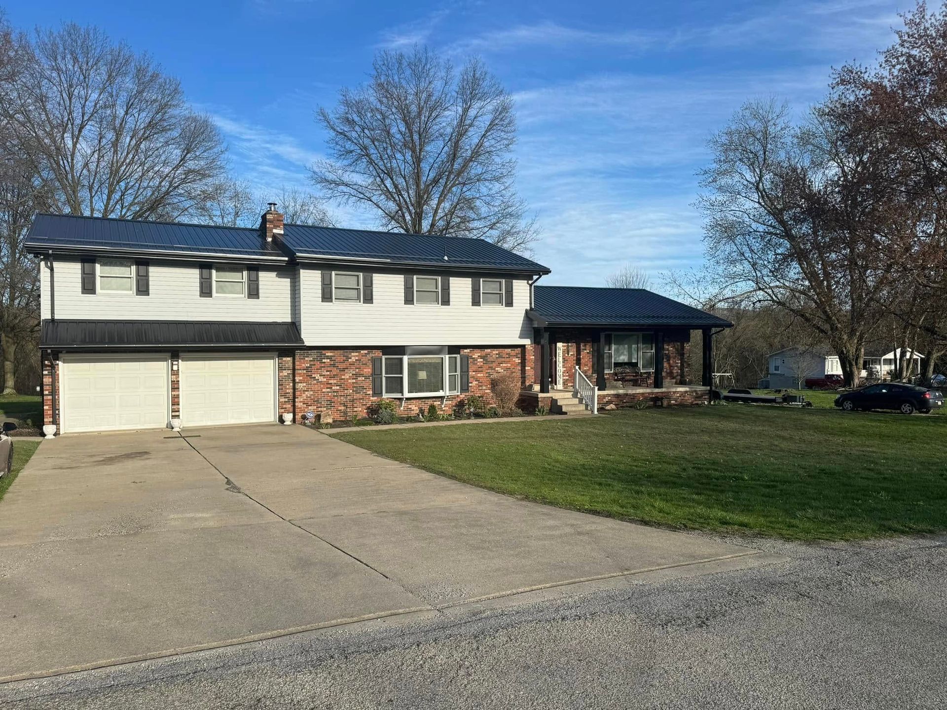 A large white house with a black roof and a car parked in front of it.