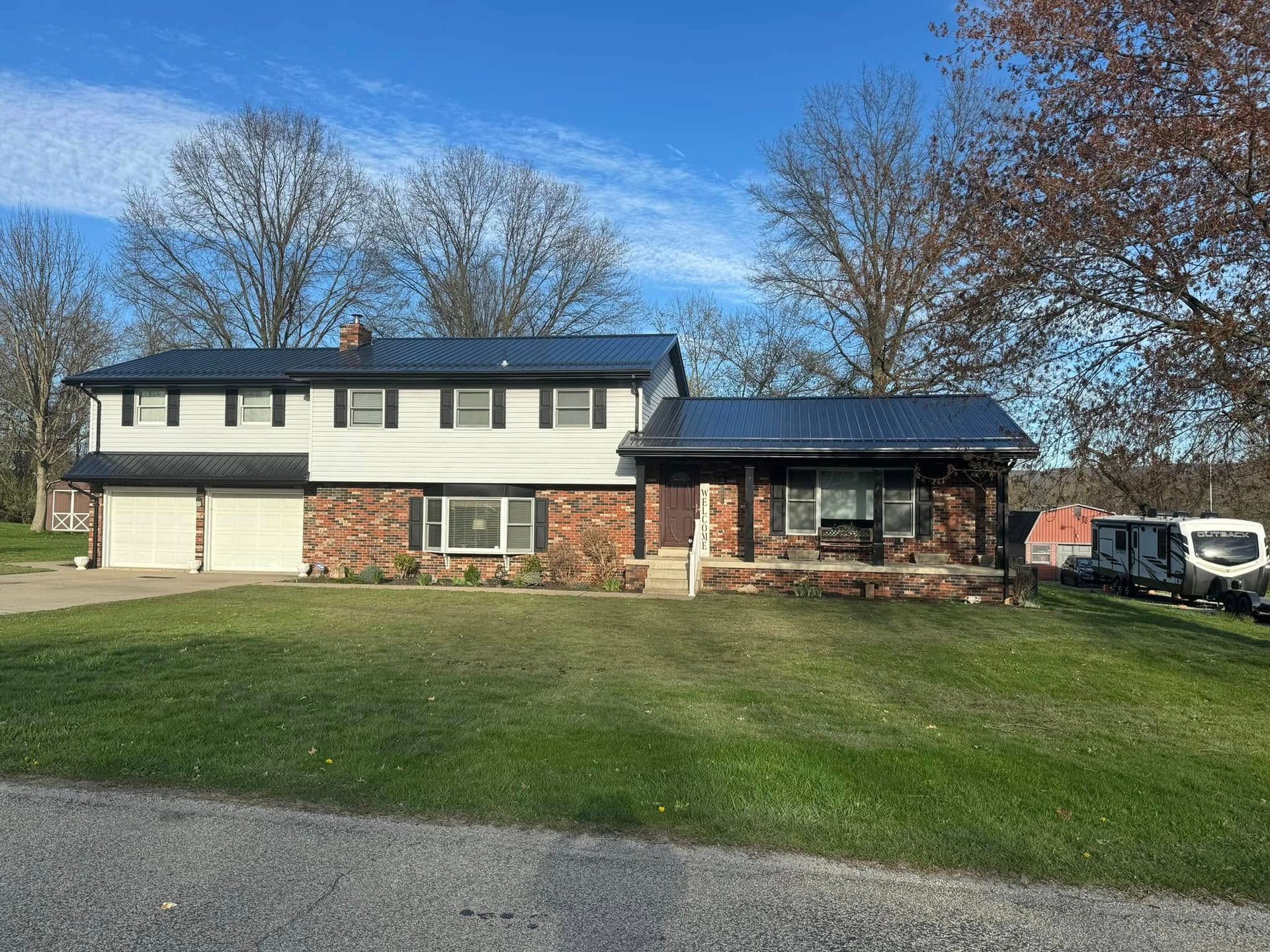 A large house with a black roof is sitting on top of a lush green field.