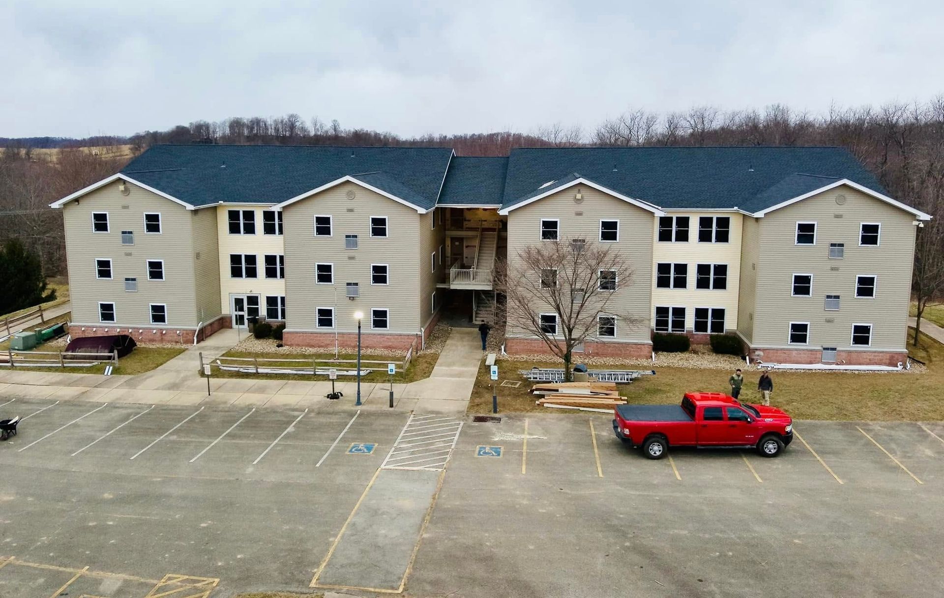 A red truck is parked in front of a large apartment building