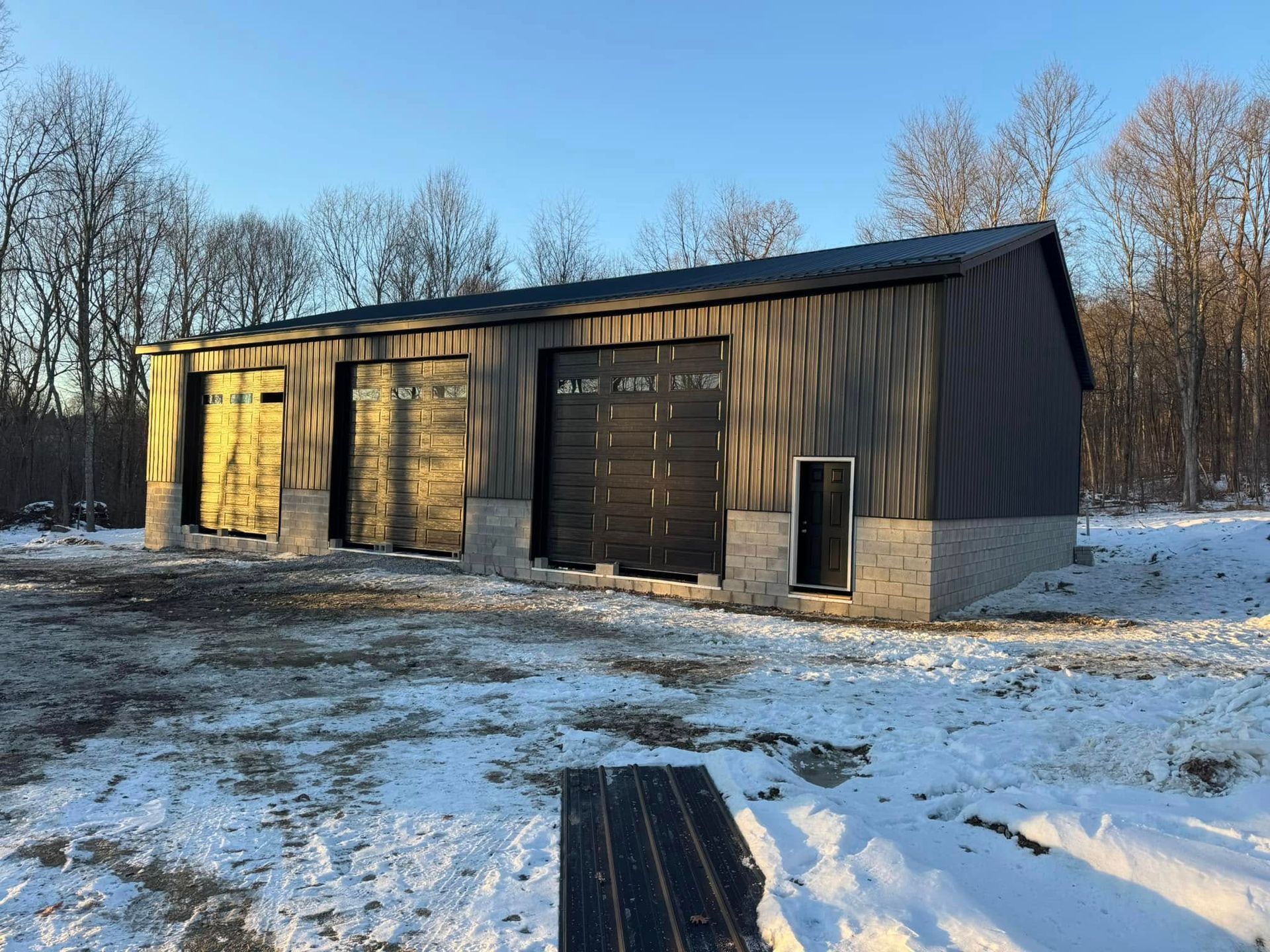 A large garage is sitting in the middle of a snowy field.