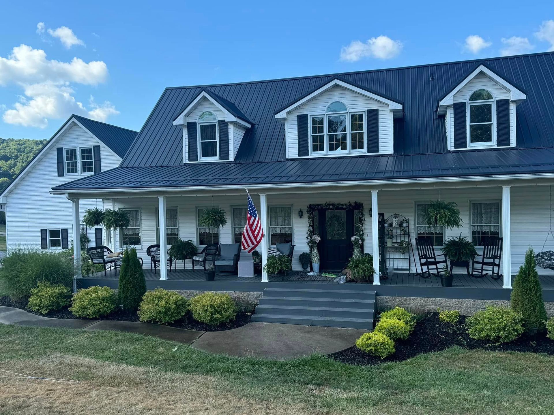 A large white house with a black roof and a porch.