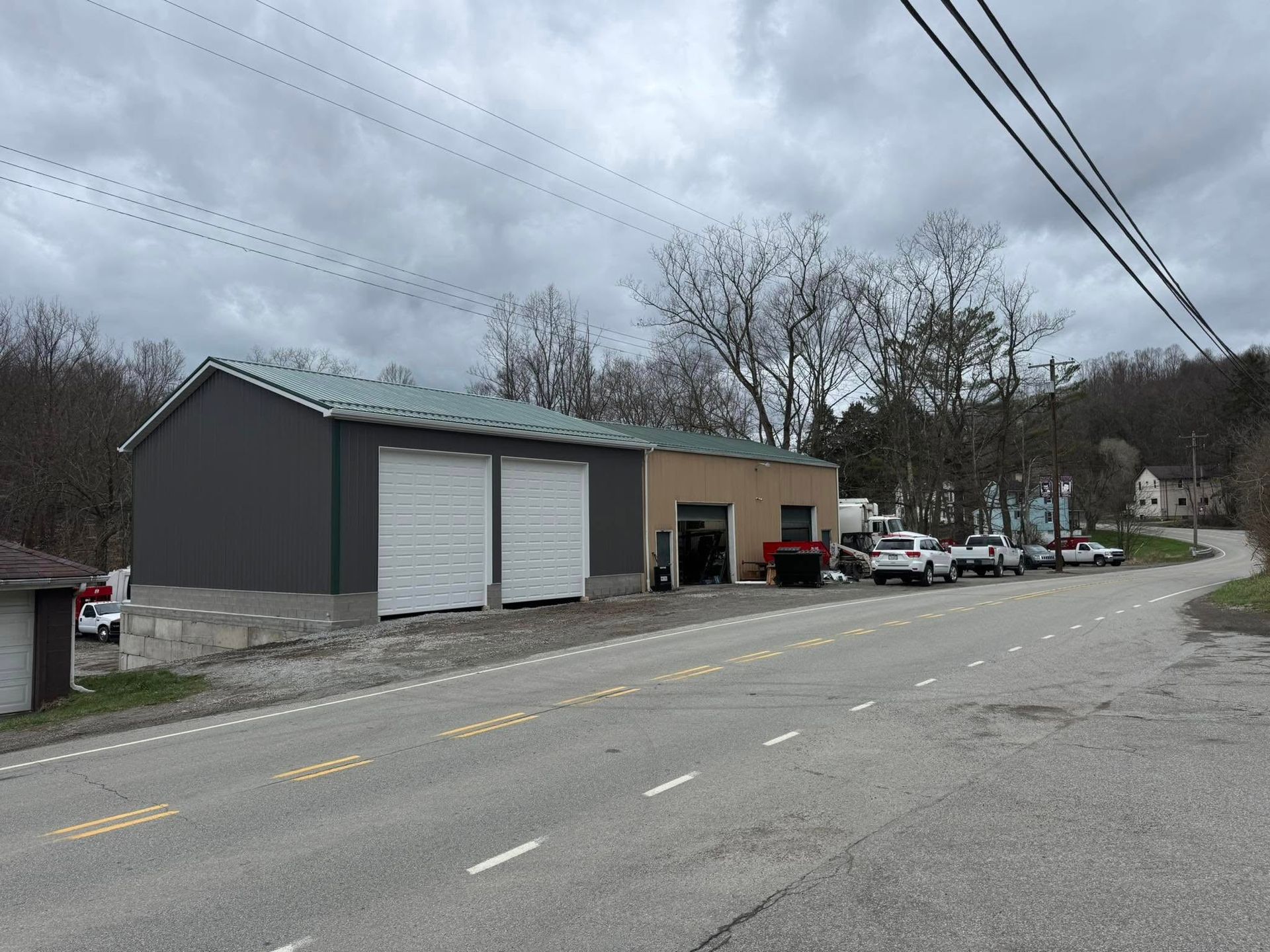 A row of trucks are parked in front of a building on the side of the road.