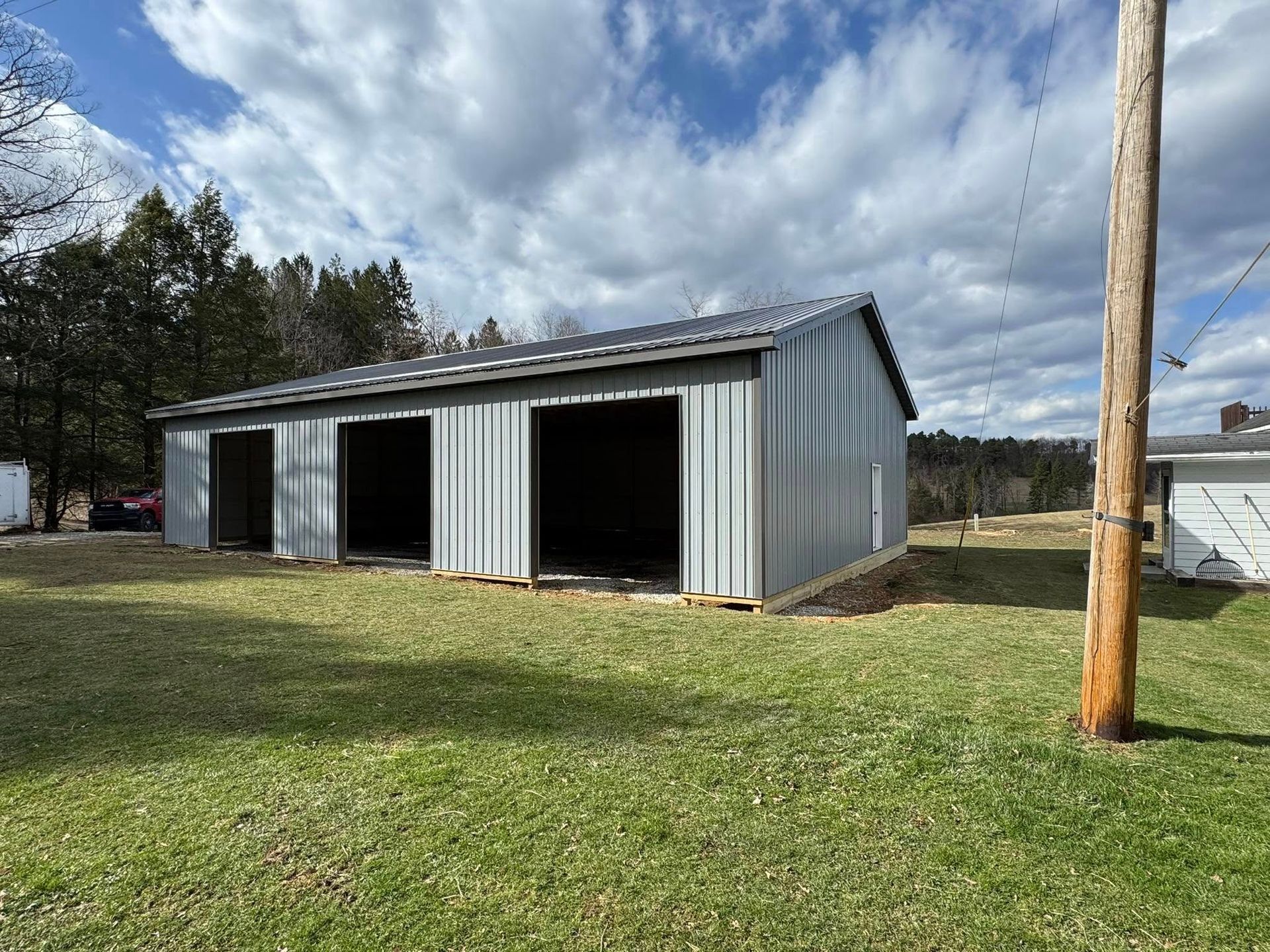 A large gray metal building is sitting in the middle of a grassy field.