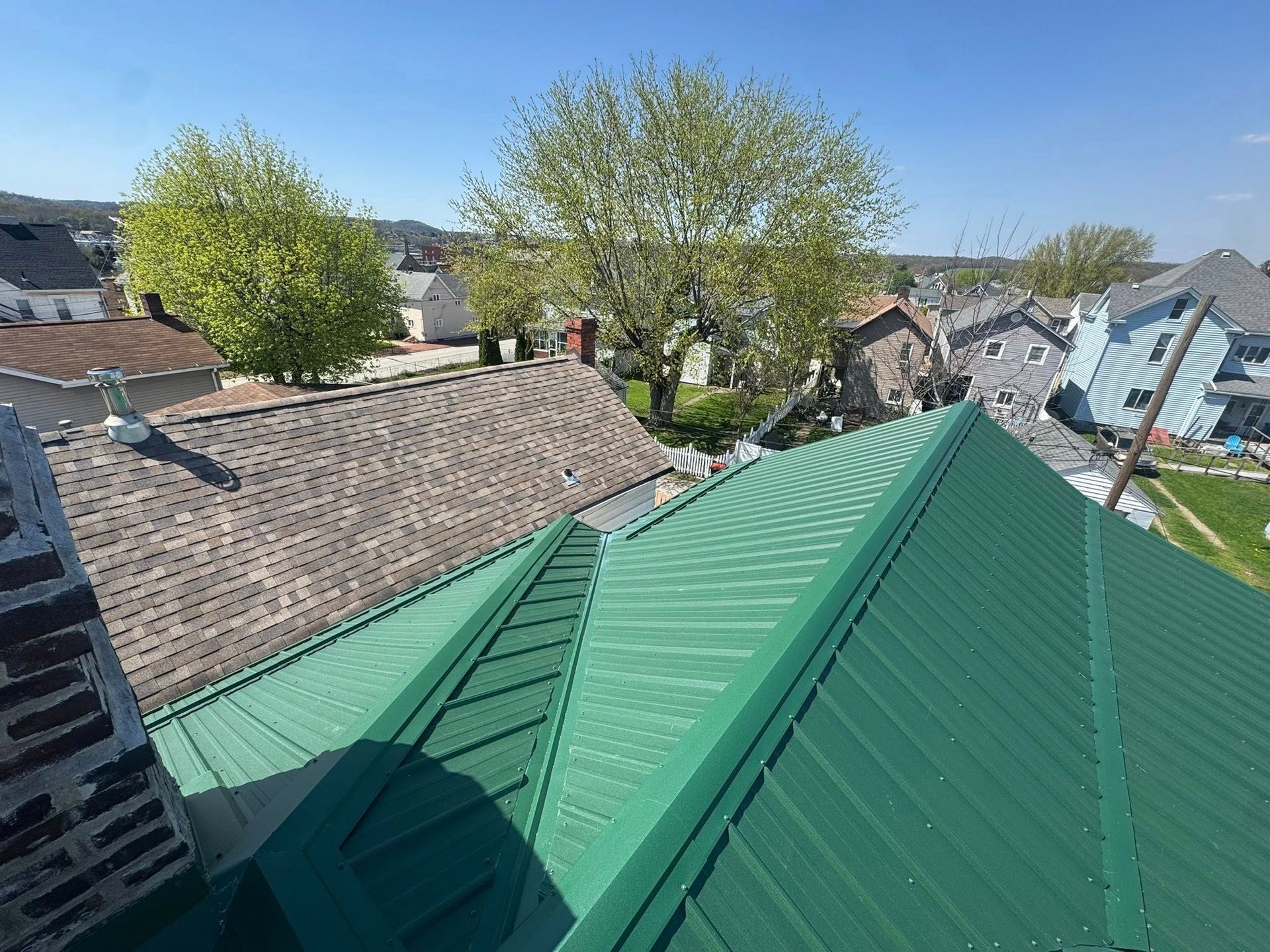 A green metal roof is sitting on top of a brick building.
